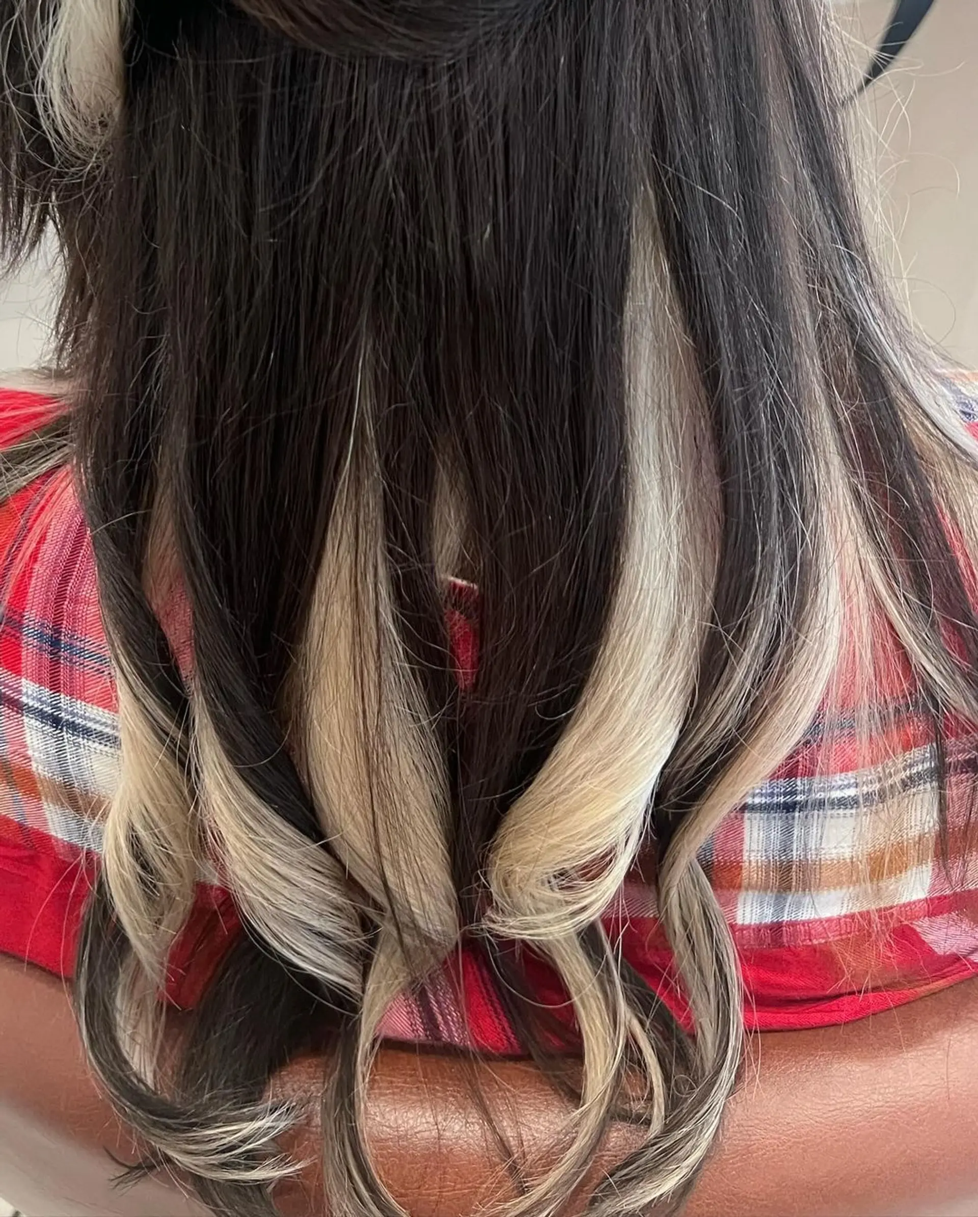 Long, wavy hairstyle with black base color and platinum blonde highlights, featuring a center part and face-framing layers for added volume and dimension. 2