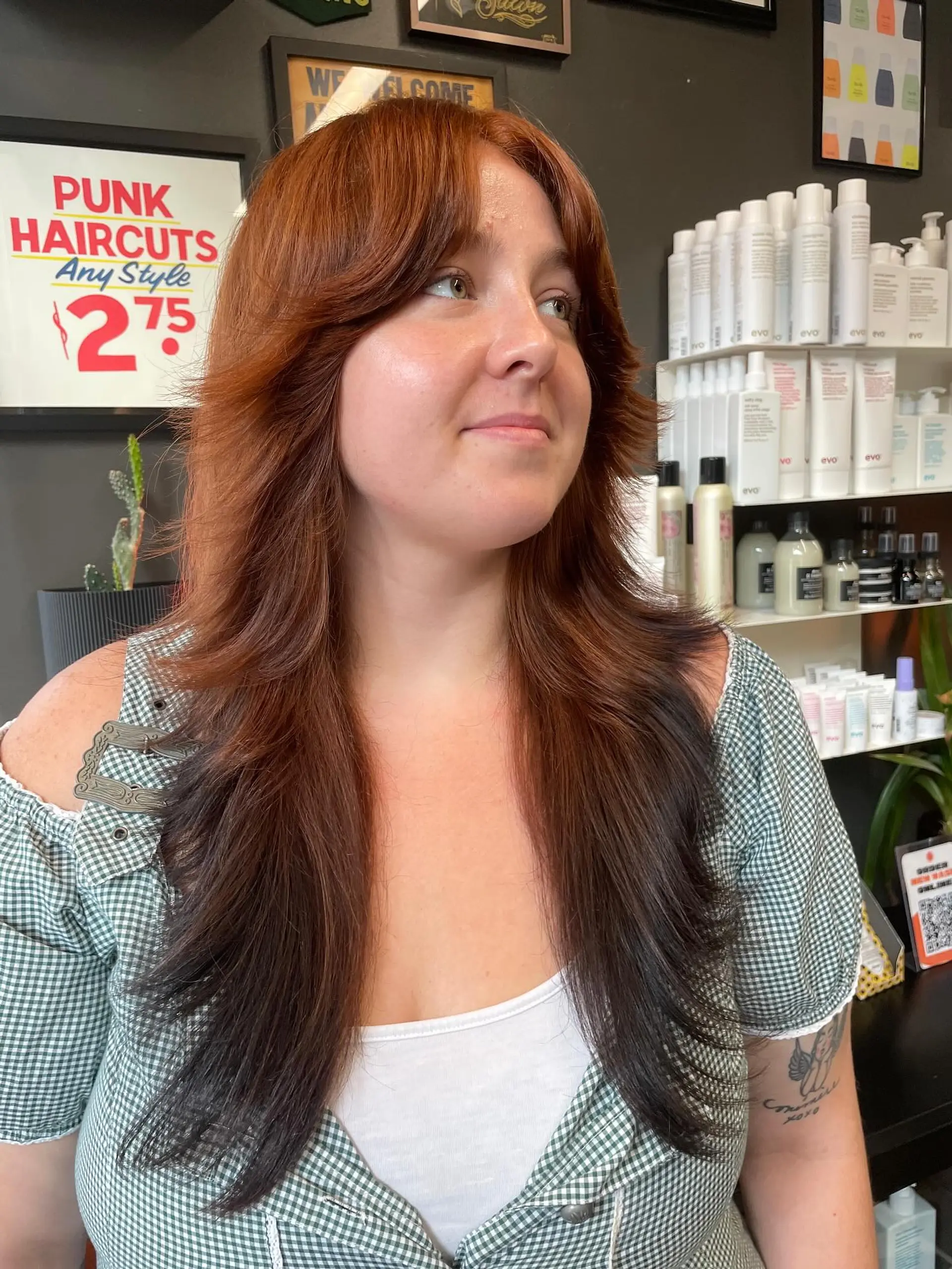 Long warm copper haircut featuring dramatic curtain bangs and feathered face-framing layers. 1