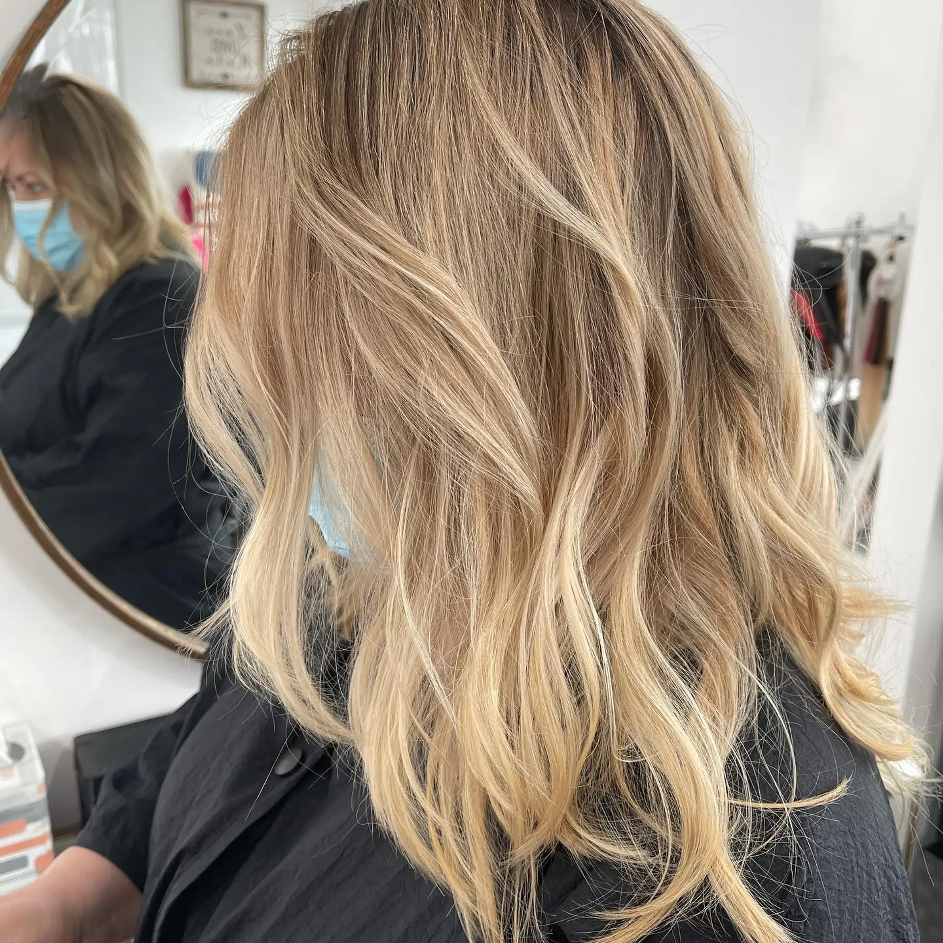 Medium-length blonde balayage styled with loose, dimensional textured waves. 1