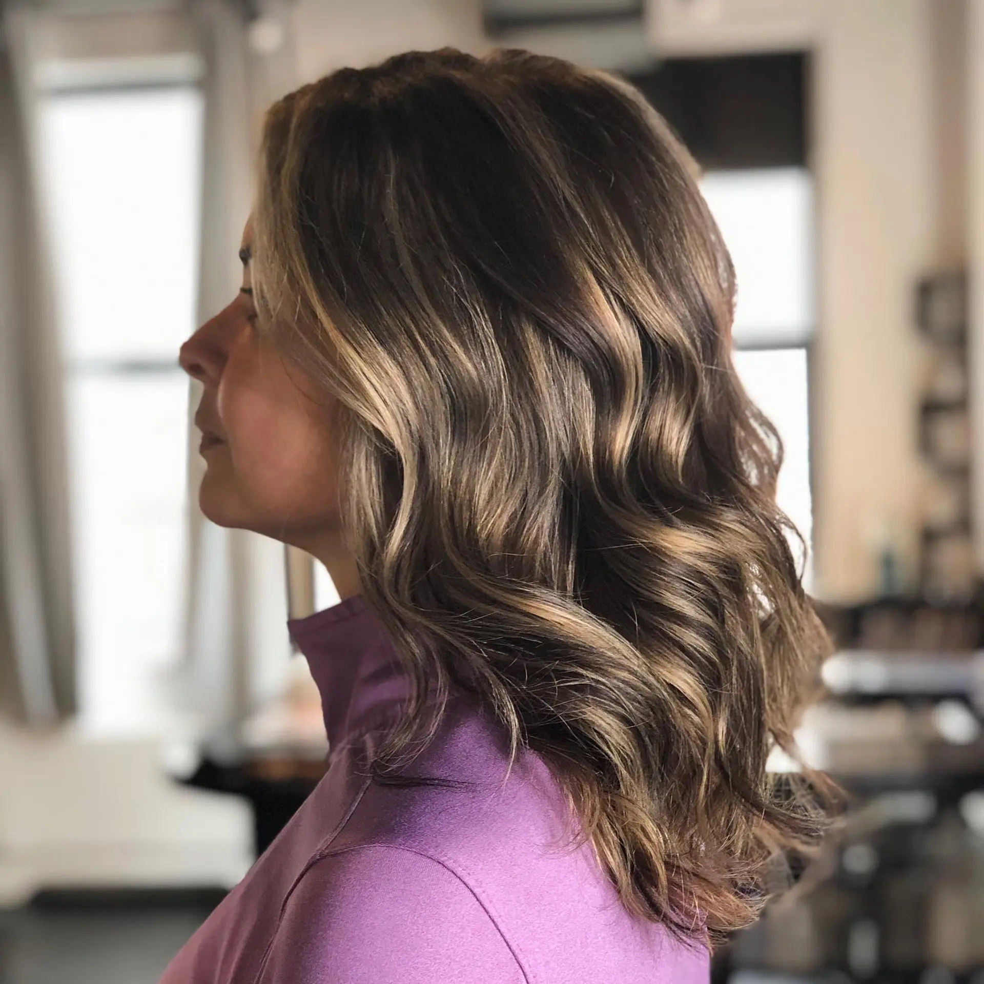 Medium-length wavy brunette hair featuring dimensional caramel and honey blonde highlights. 1