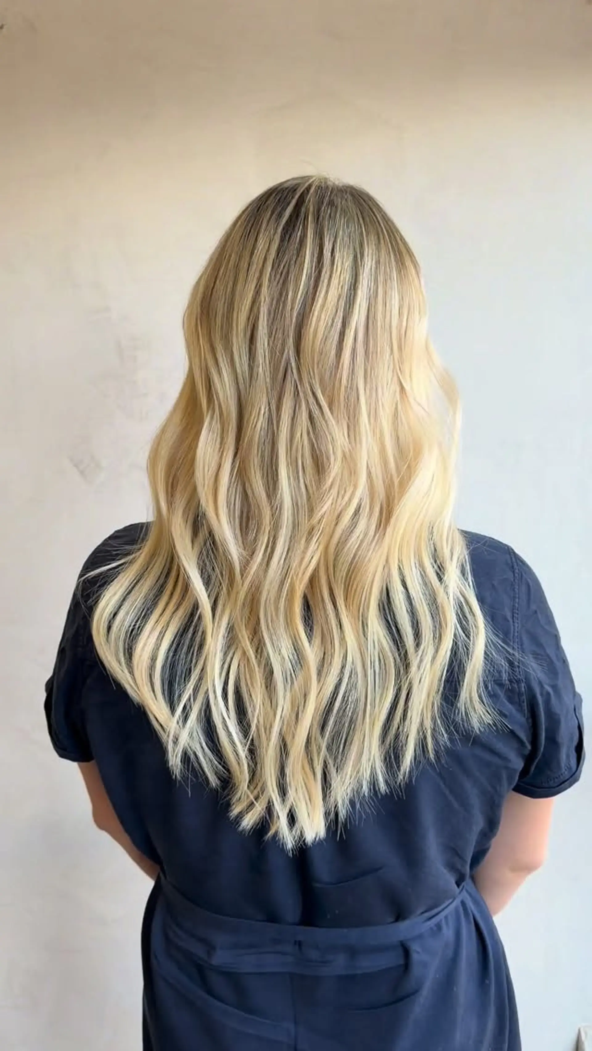 Long dimensional blonde hair styled in soft, textured waves cascading down the back. 1