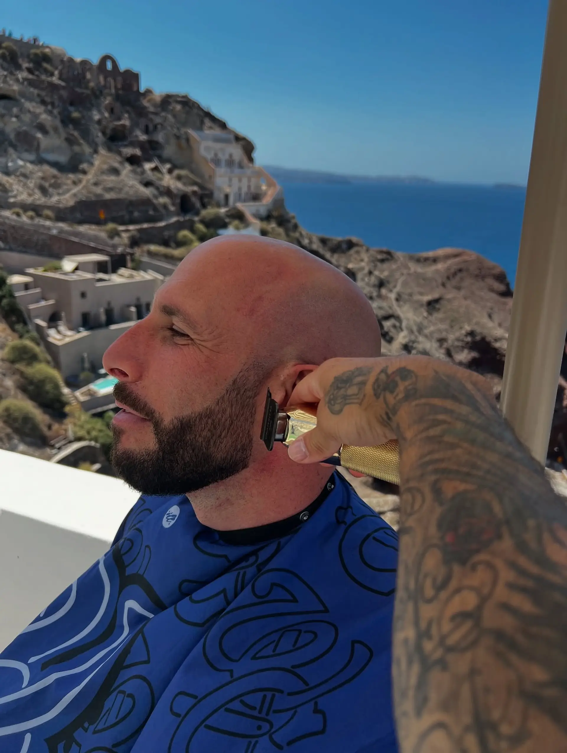 A completely smooth bald head shave paired with a sharply defined, sculpted dark beard. 1