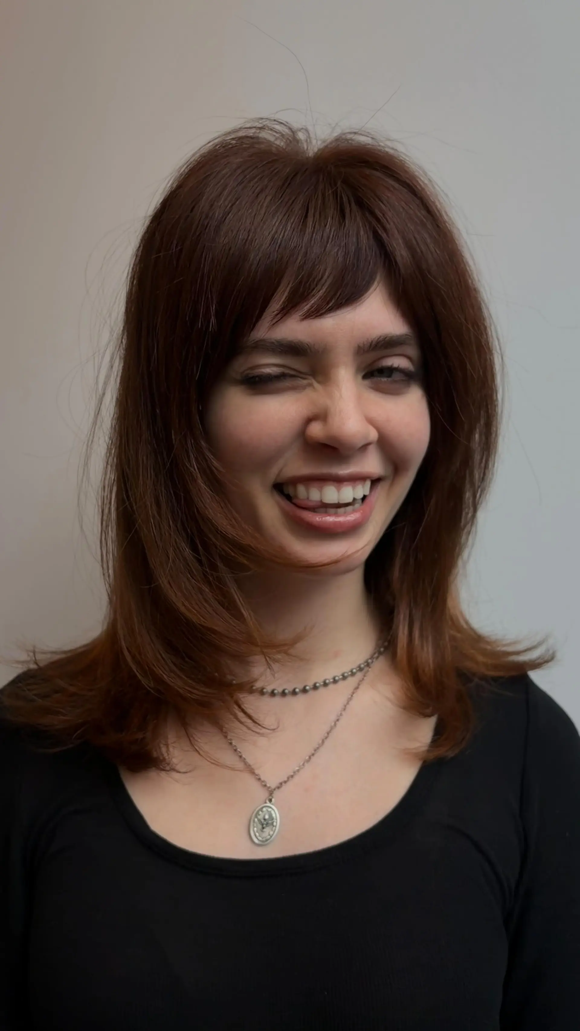 Medium-length copper auburn layered haircut with textured front bangs and softly flipped ends. 1