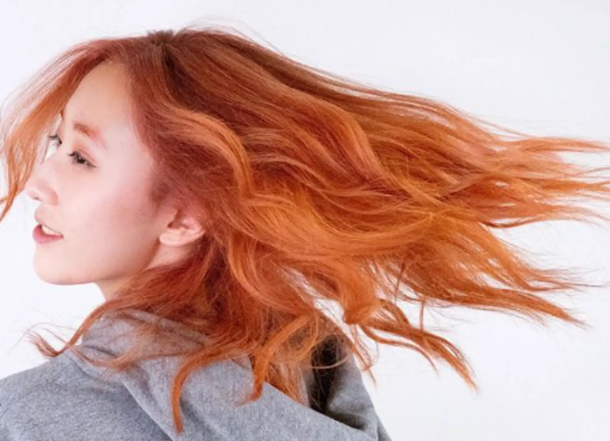 Long, wavy hair with a vibrant copper and orange hue, featuring voluminous waves and textured layers that flow dynamically.