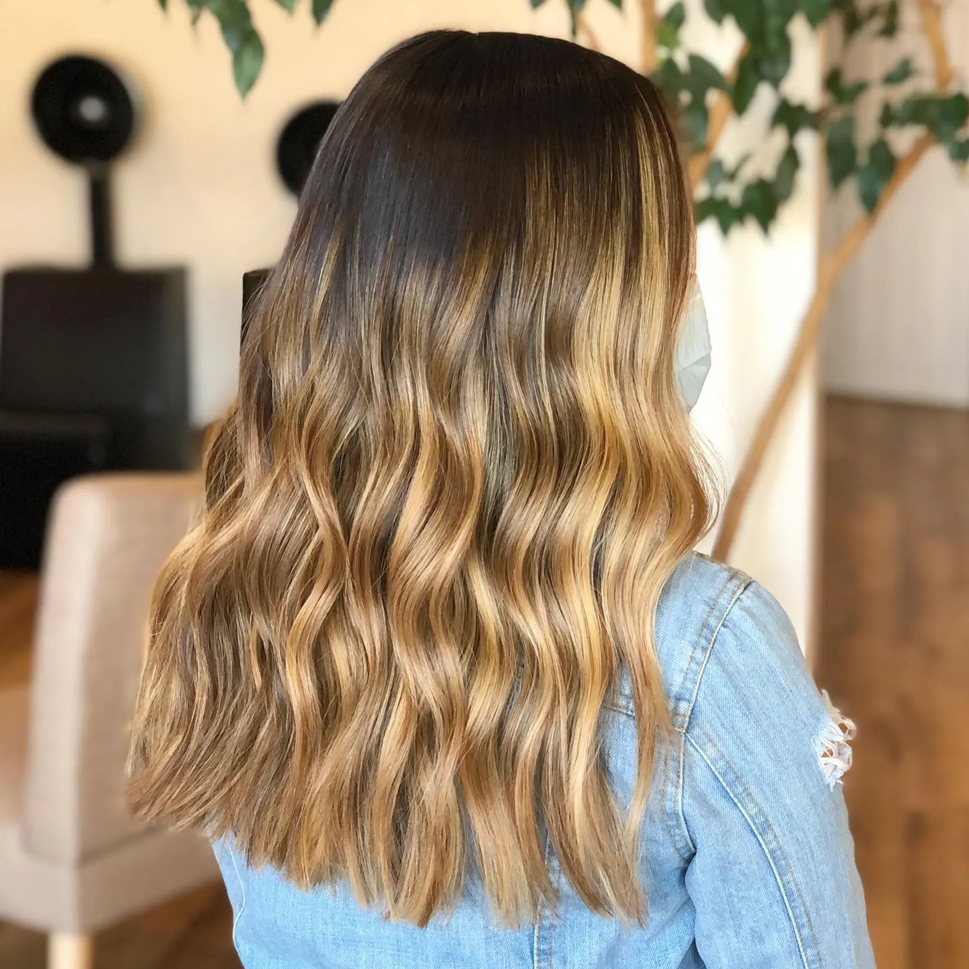 Long brunette hair featuring a seamless warm honey blonde balayage styled in loose, textured waves. 1