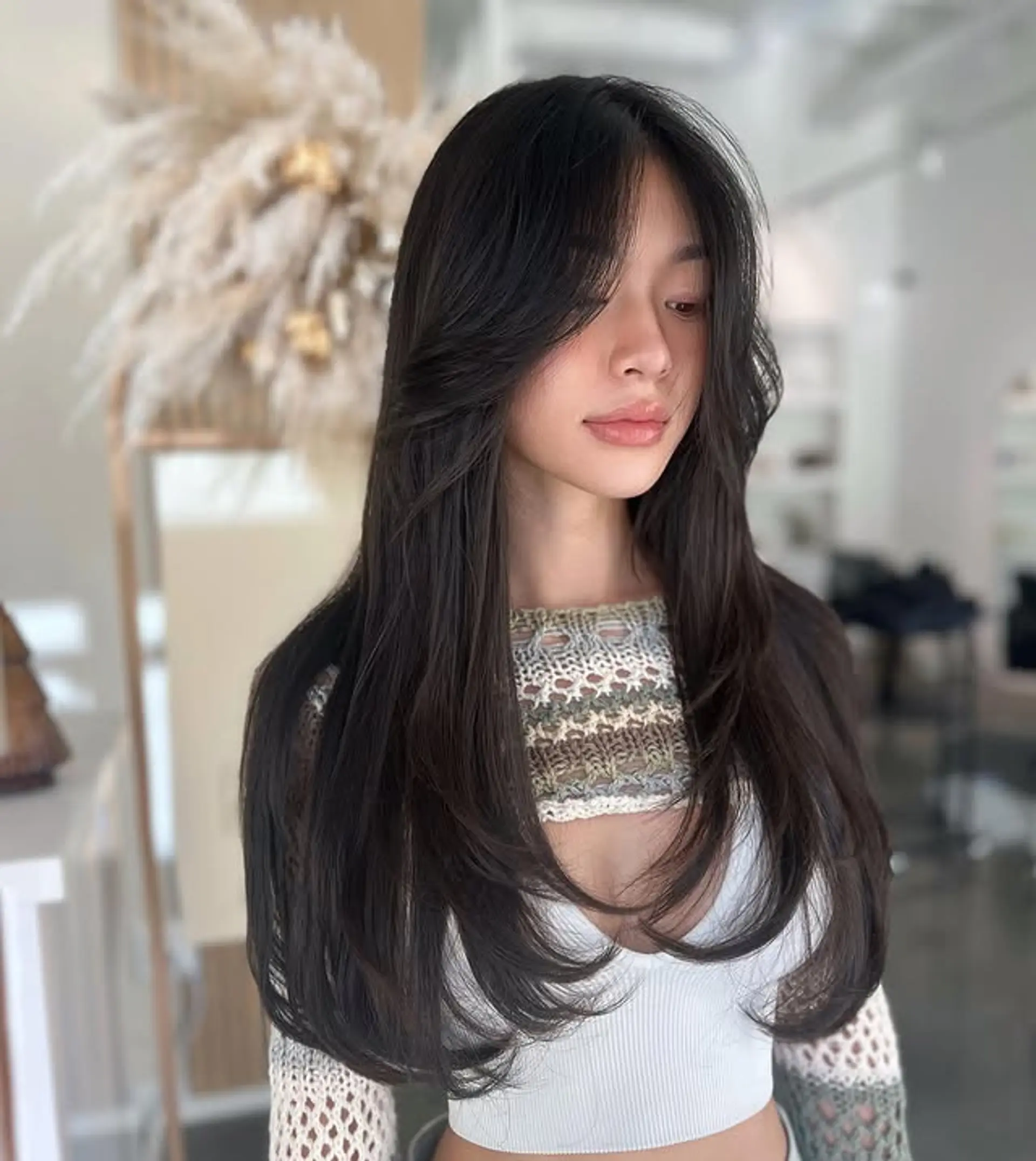 A beautiful long layered haircut with soft, flowing layers throughout and flattering curtain bangs that frame the face, adding volume and a modern touch. 1