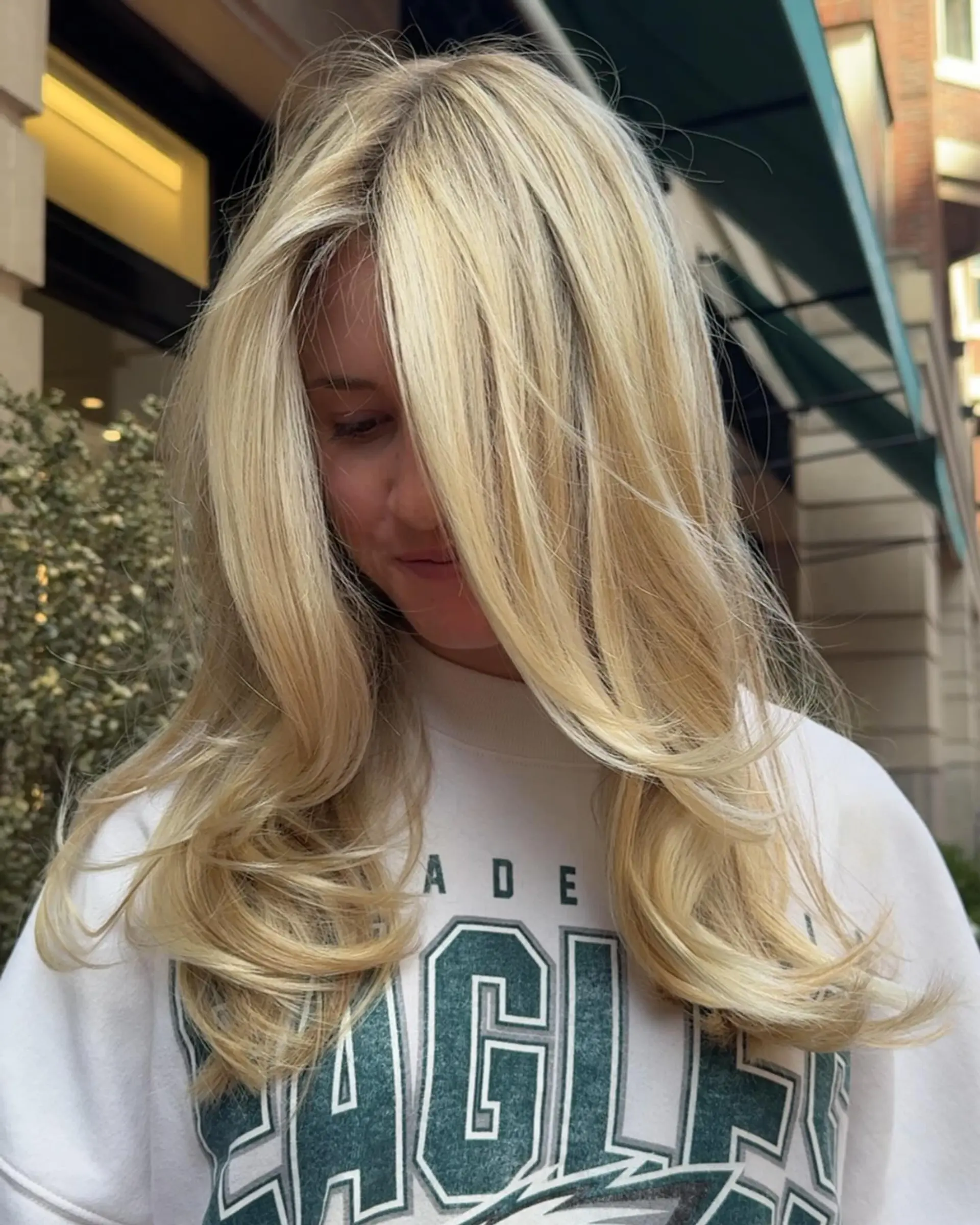 Long, bright cool-blonde hair styled with face-framing layers and a voluminous, soft blowout curving at the ends. 1
