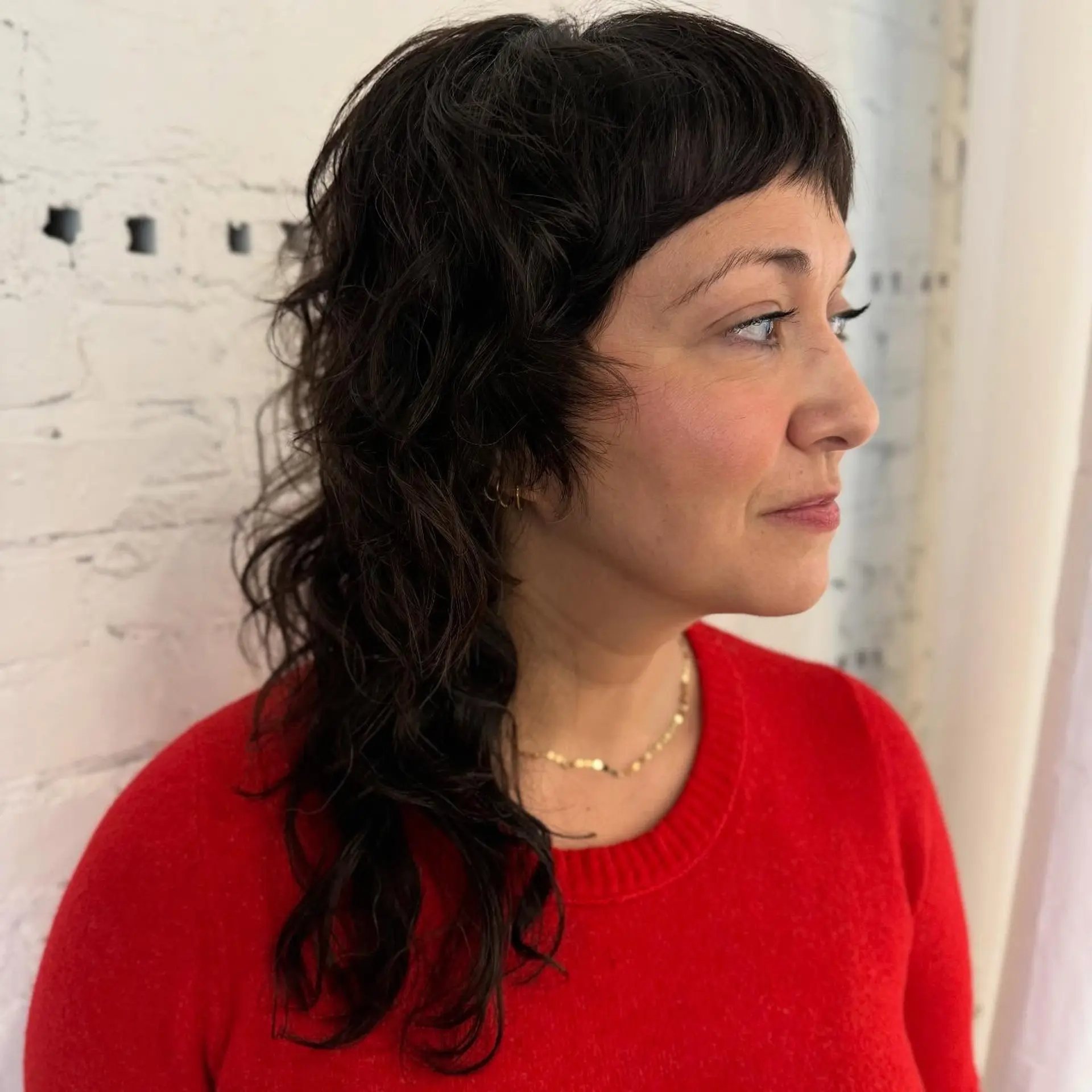 A dark brown wavy shag cut with blunt micro bangs and soft face-framing layers. 1