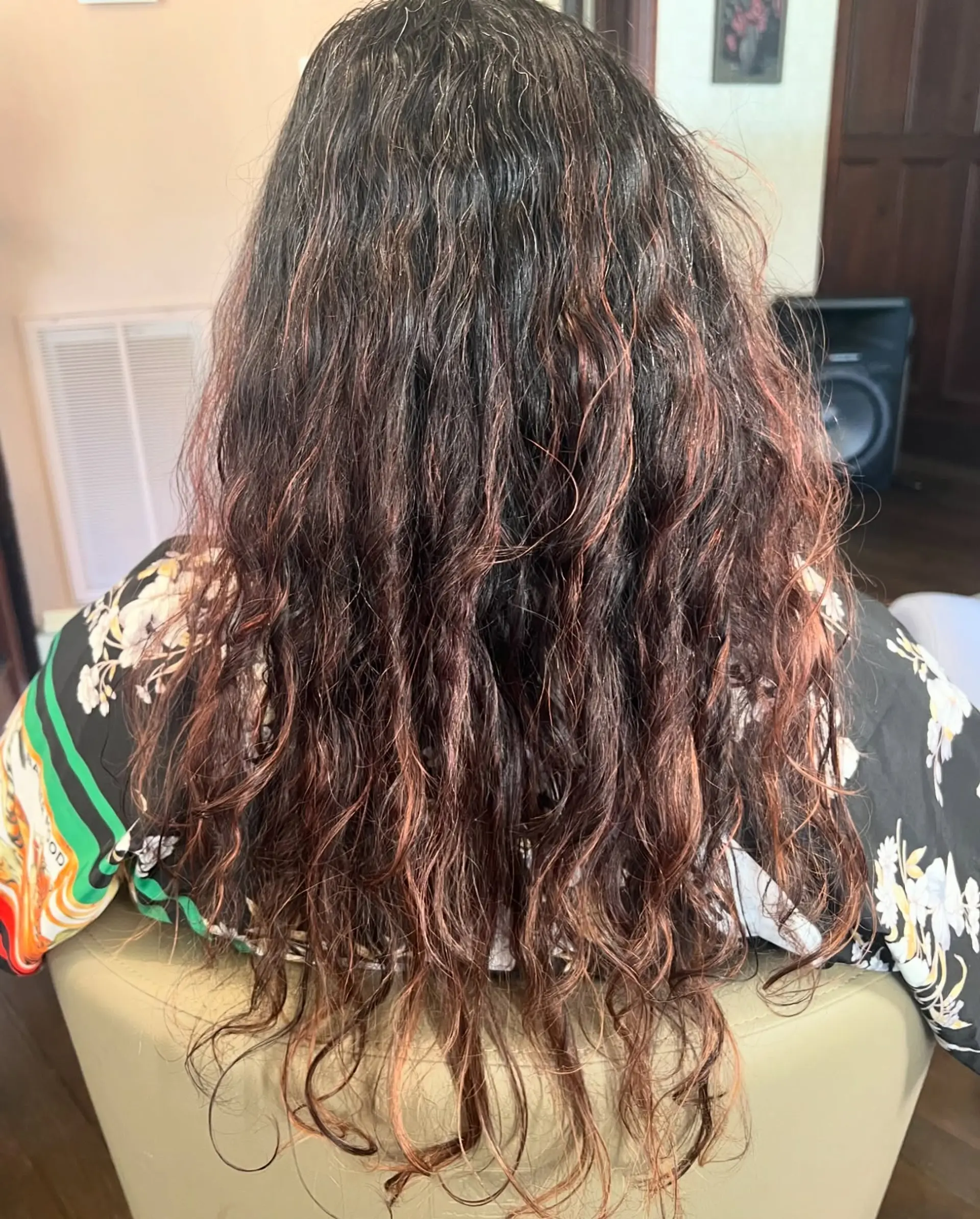 Long curly hair styled with a vivid cherry red or magenta balayage, featuring a deep, dark root that transitions into bright, playful curls for a dynamic and textured look. 3