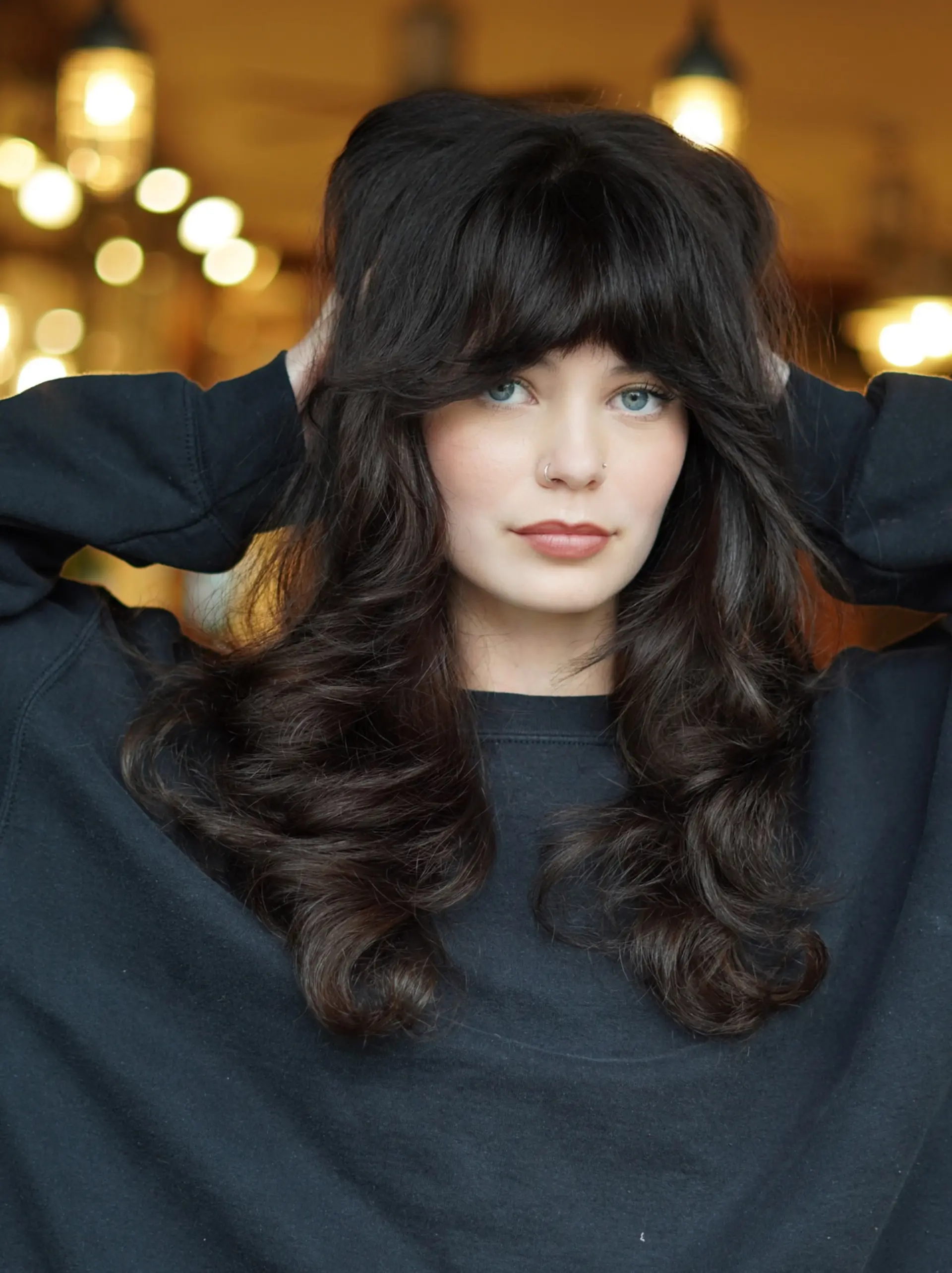 A voluminous retro-inspired modern shag cut featuring full feathered curtain bangs and soft, bouncy layered waves. 1