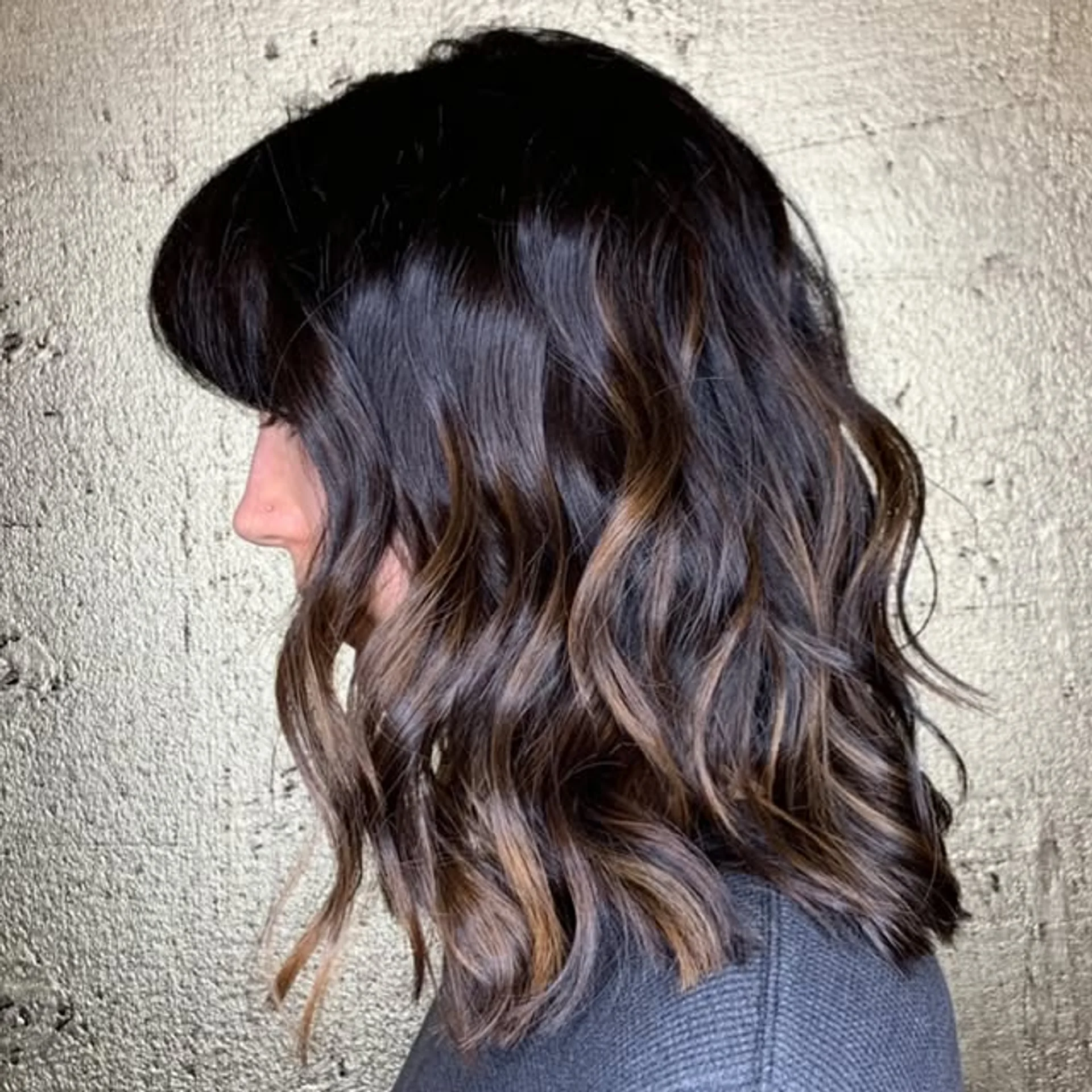 A medium-length wavy lob featuring chocolate brown hair and long curtain bangs seamlessly blending into face-framing layers. - Preview 1