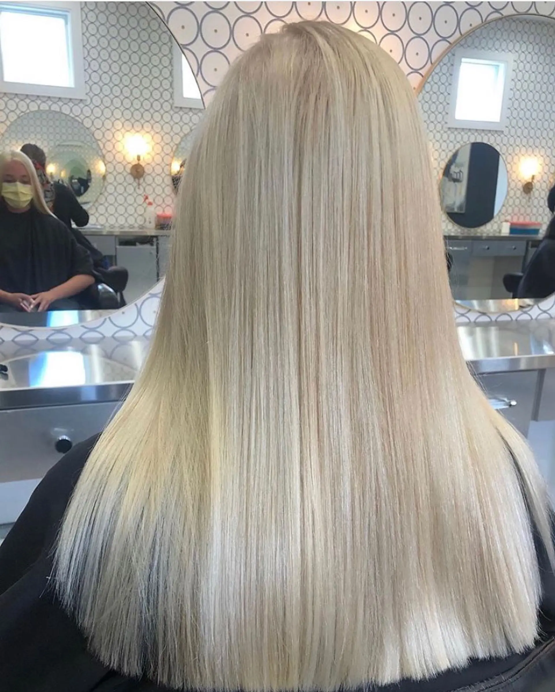 Straight, sleek platinum blonde hair cascading down the back with blunt, healthy ends. 1