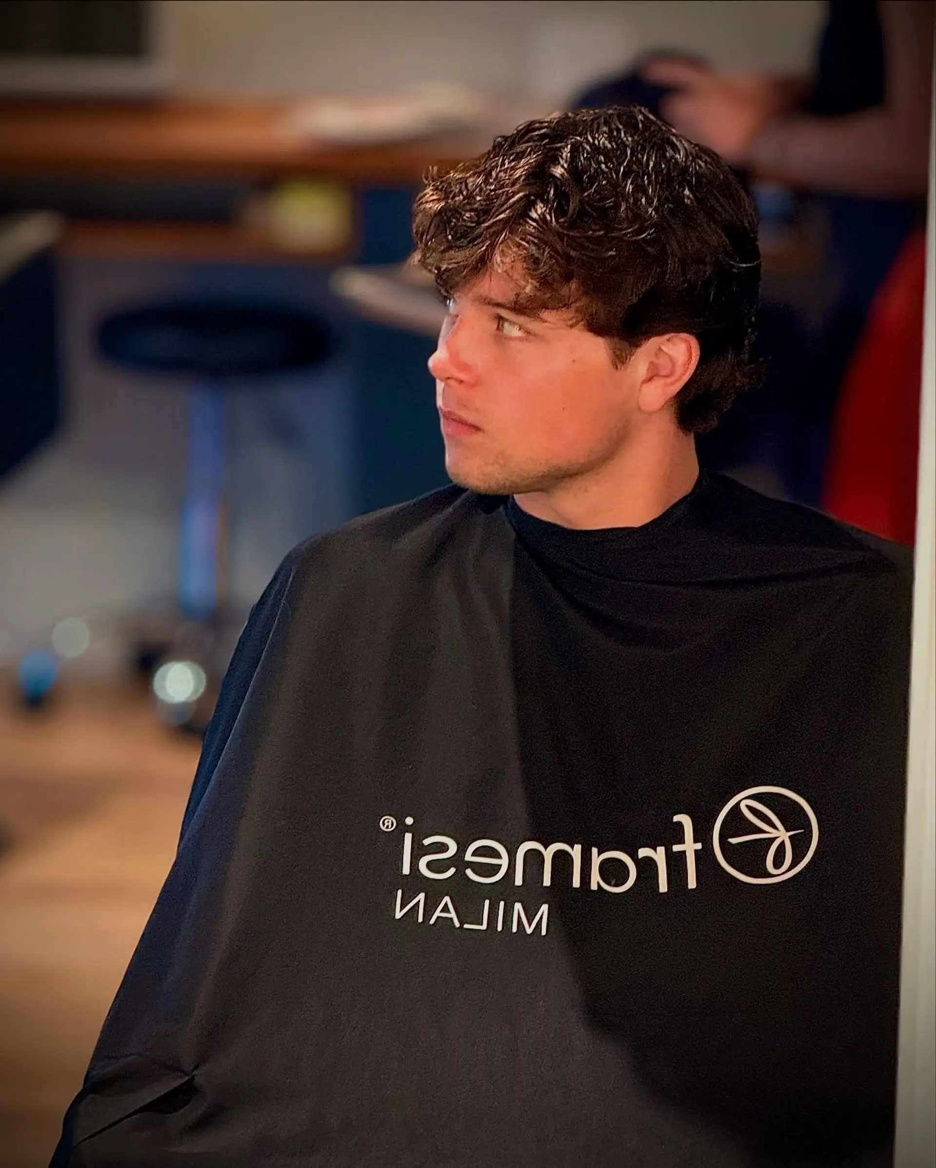 A textured short men's haircut featuring natural waves, softly tapered sides, and a piecey, forward-styled fringe. 1