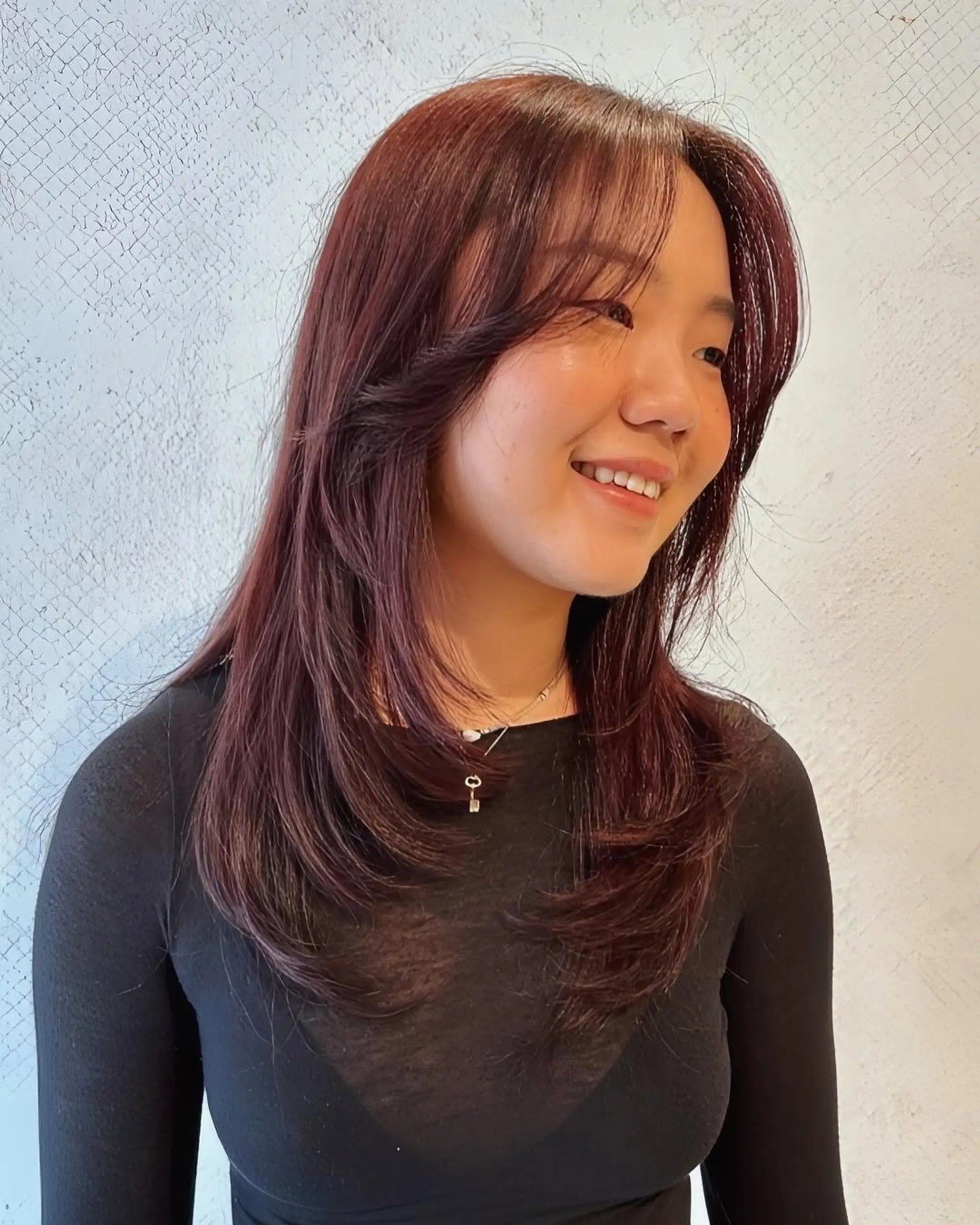 Long, rich auburn hair with feathered layers and side-swept bangs, exuding a glossy finish.