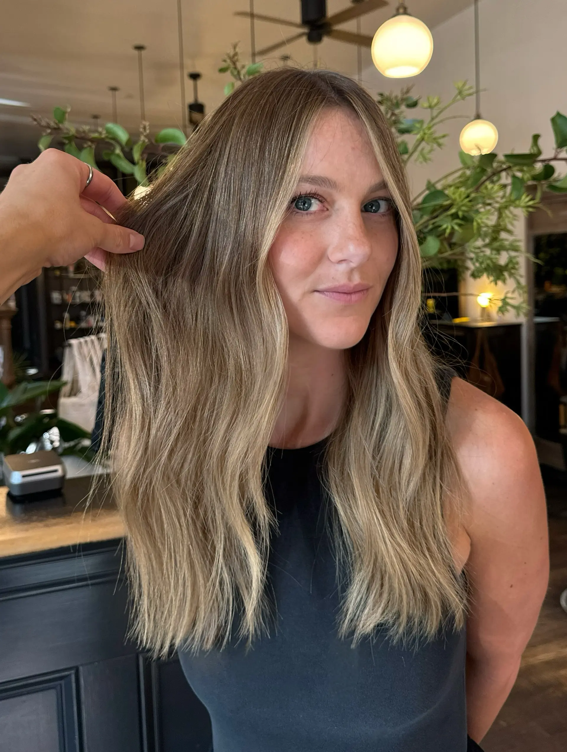 Long, dimensional neutral bronde hair featuring a soft blend of highlights and lowlights with brighter face-framing pieces. 1