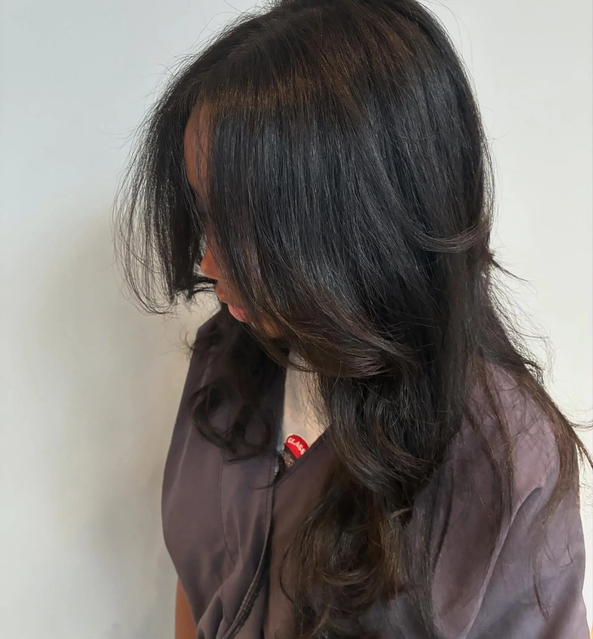 Long dark layered haircut styled with a bouncy, voluminous blowout and soft curved face-framing ends. 1