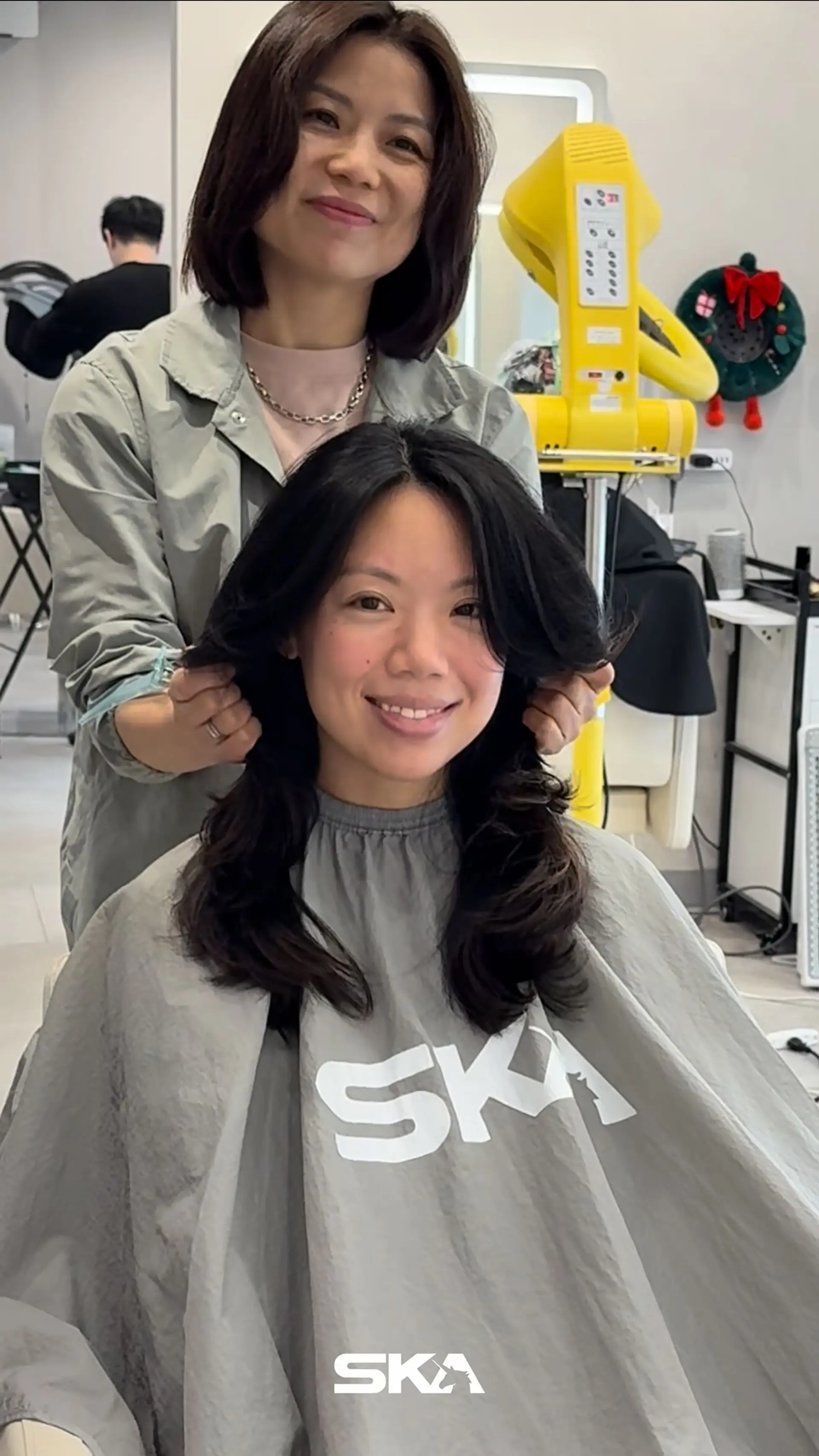 Medium-to-long layered haircut styled with voluminous curtain bangs and soft outward waves. 1