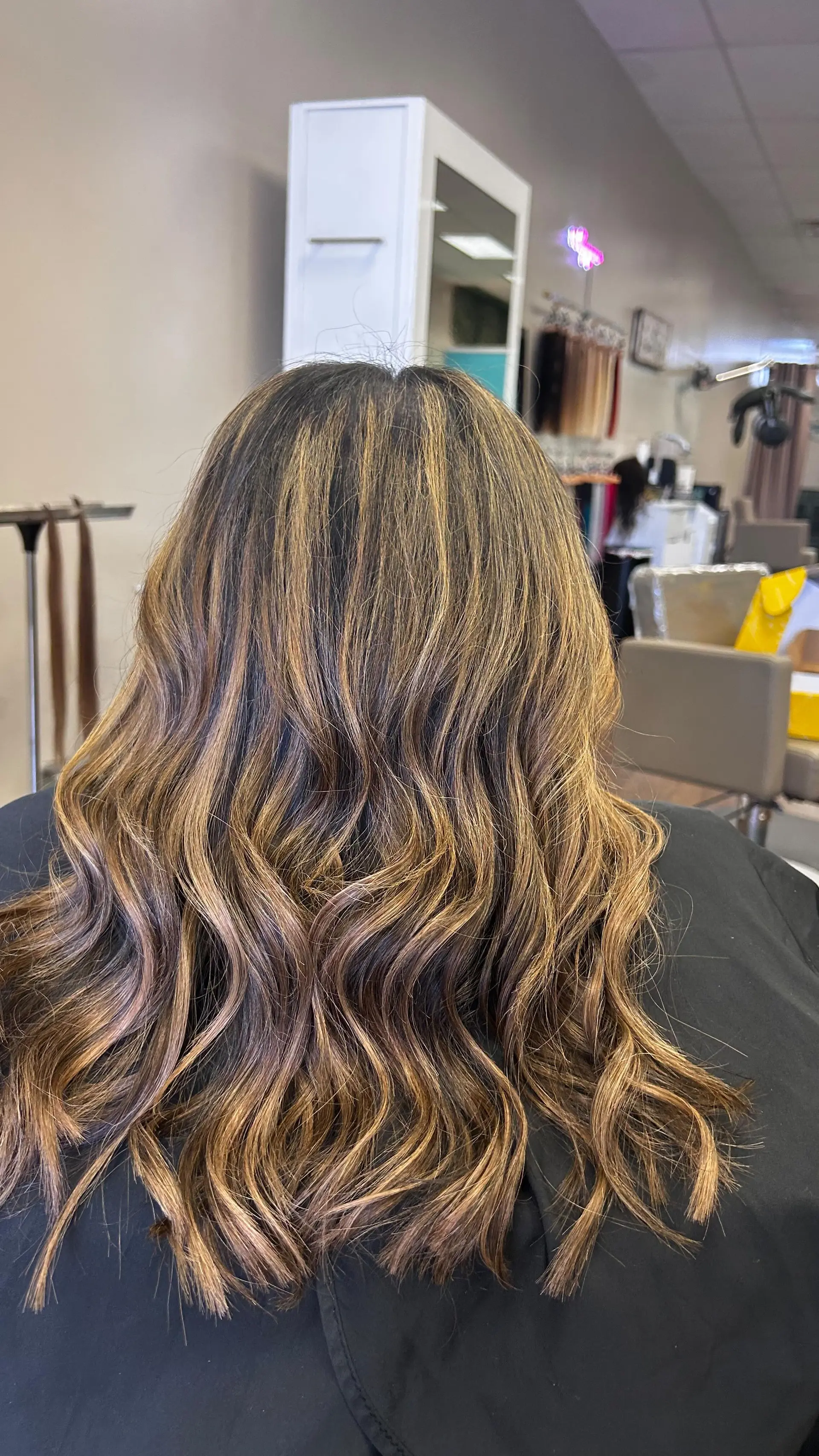 Long dark brunette hair styled with soft, tousled waves and dimensional caramel highlights. 1