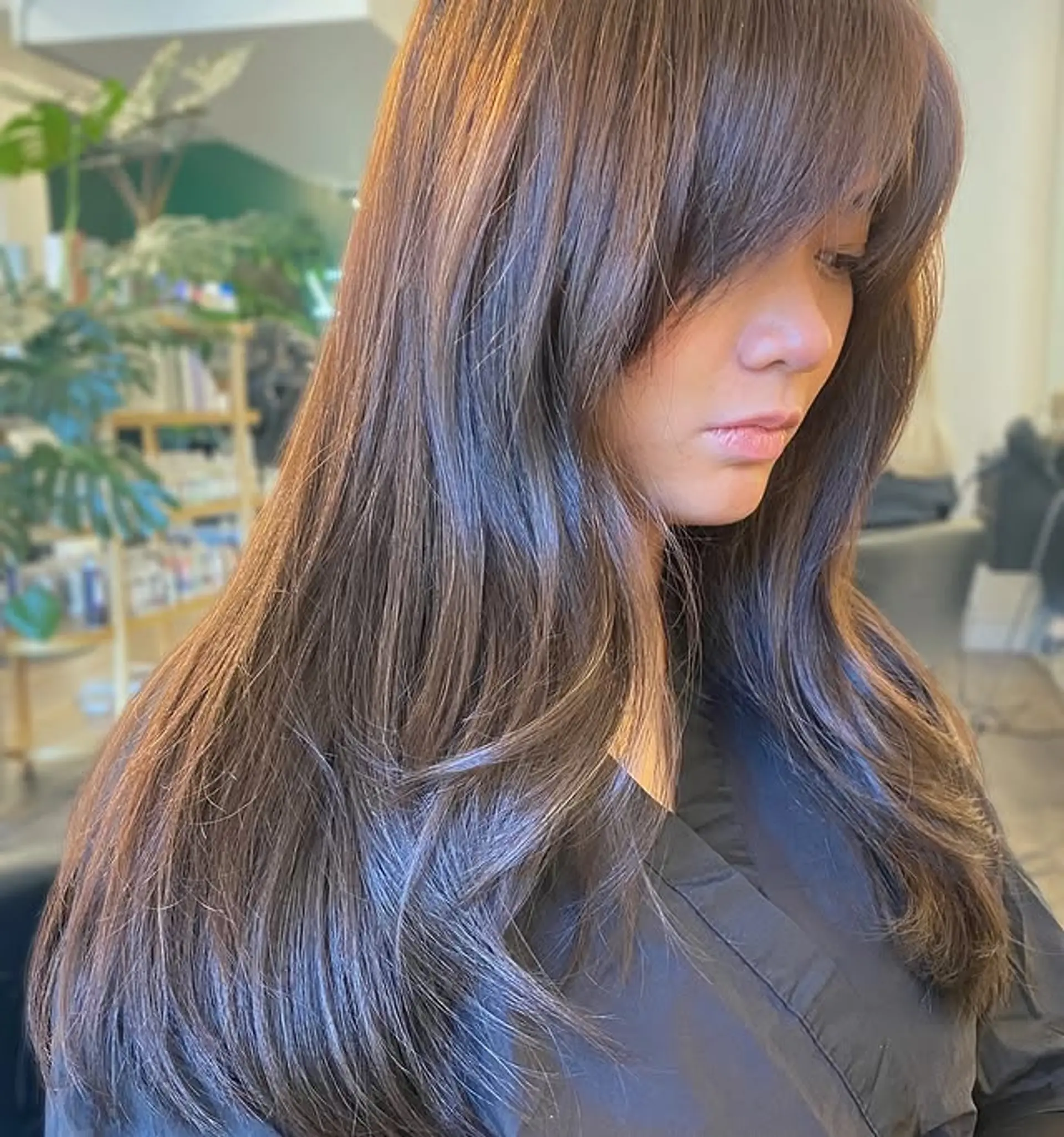 A long, layered hairstyle with face-framing curtain bangs. 1