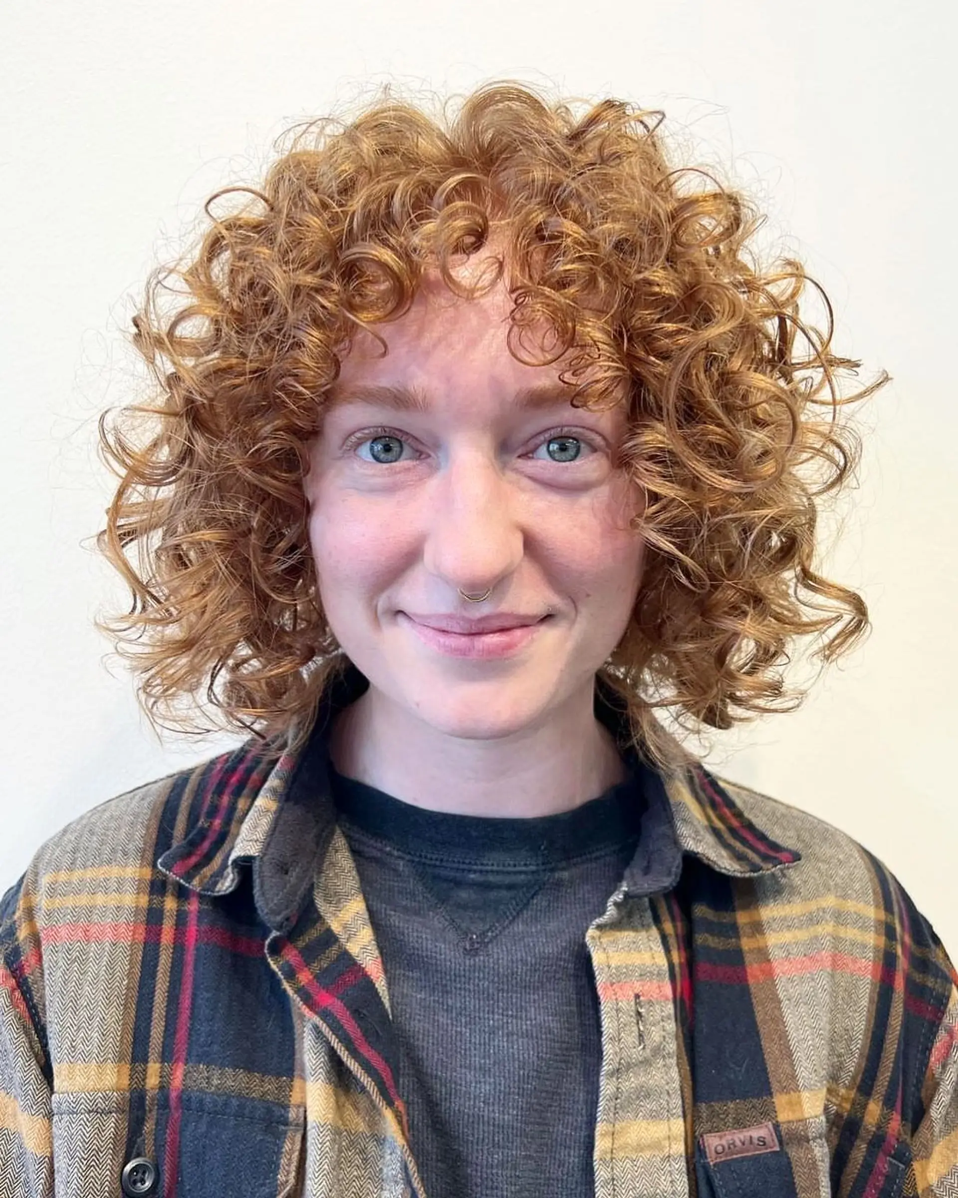 A rounded, voluminous curly bob featuring defined ringlets and full curly bangs. 1