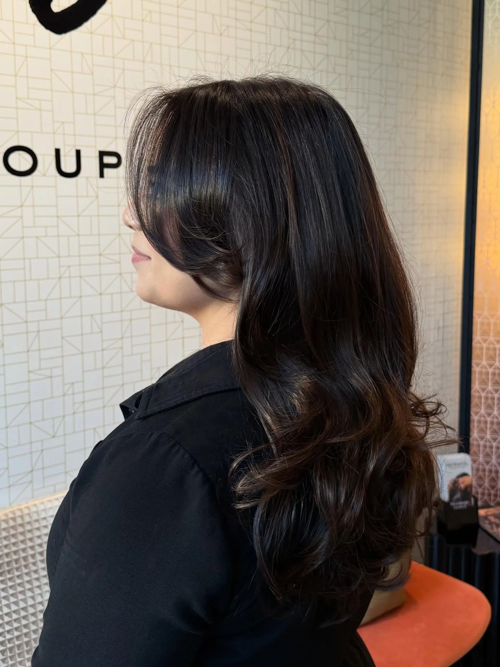 Long dark brunette hair styled with subtle dimension, soft curled ends, and sweeping face-framing layers. 1