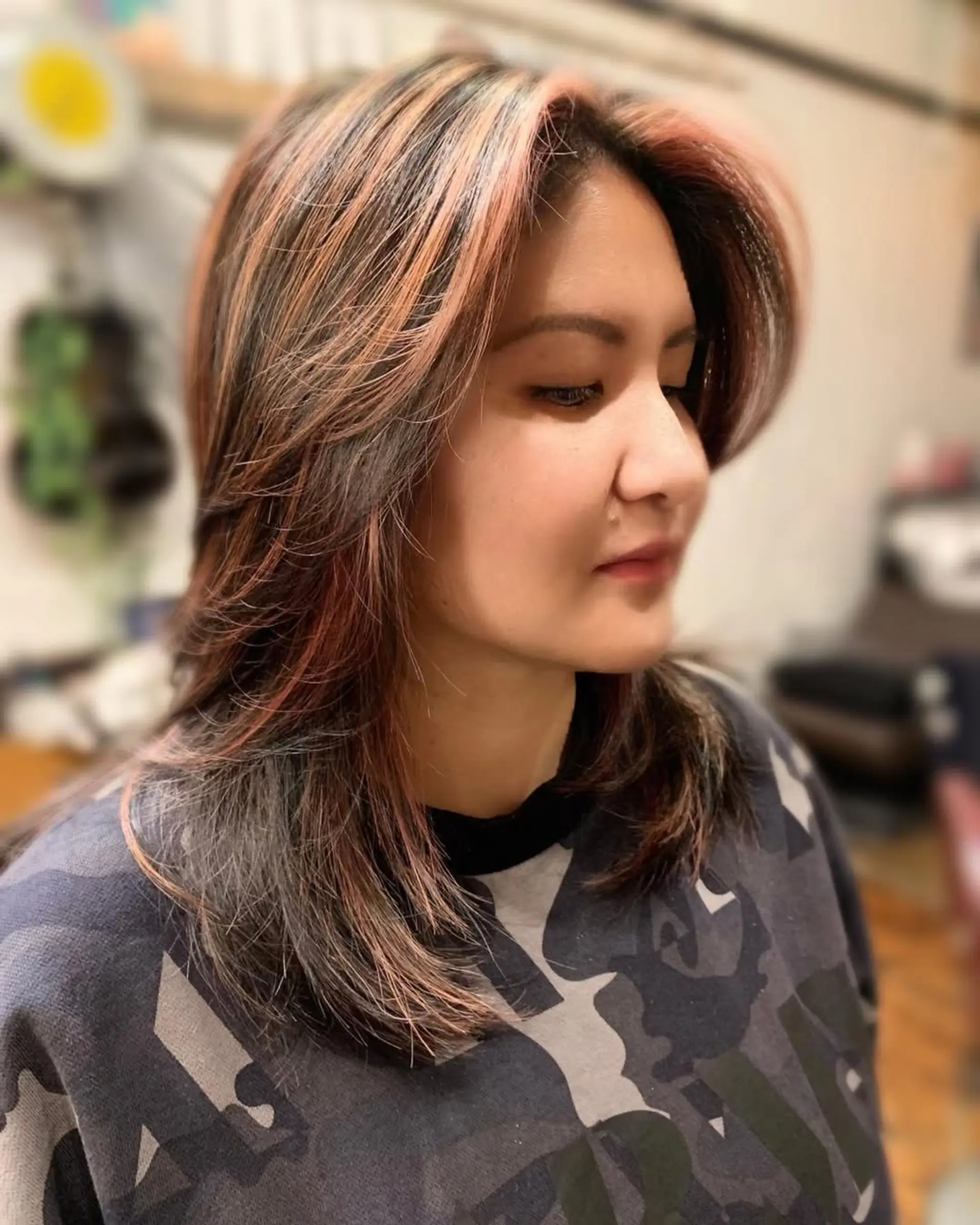 A medium-length layered haircut with copper and blonde highlights, styled with face-framing layers. 1