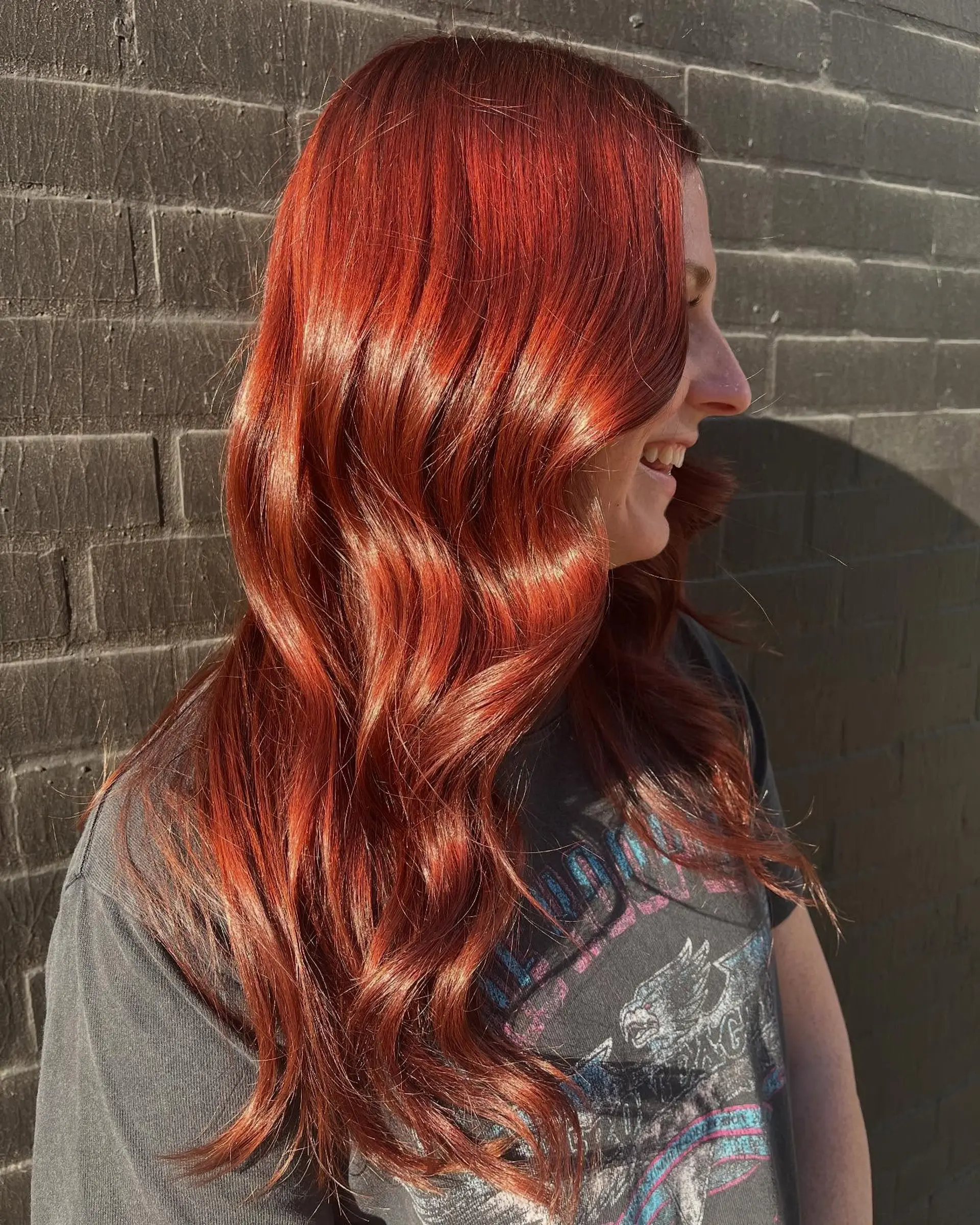 Glossy, vibrant red hair styled into loose, elegant waves that catch natural sunlight. 1