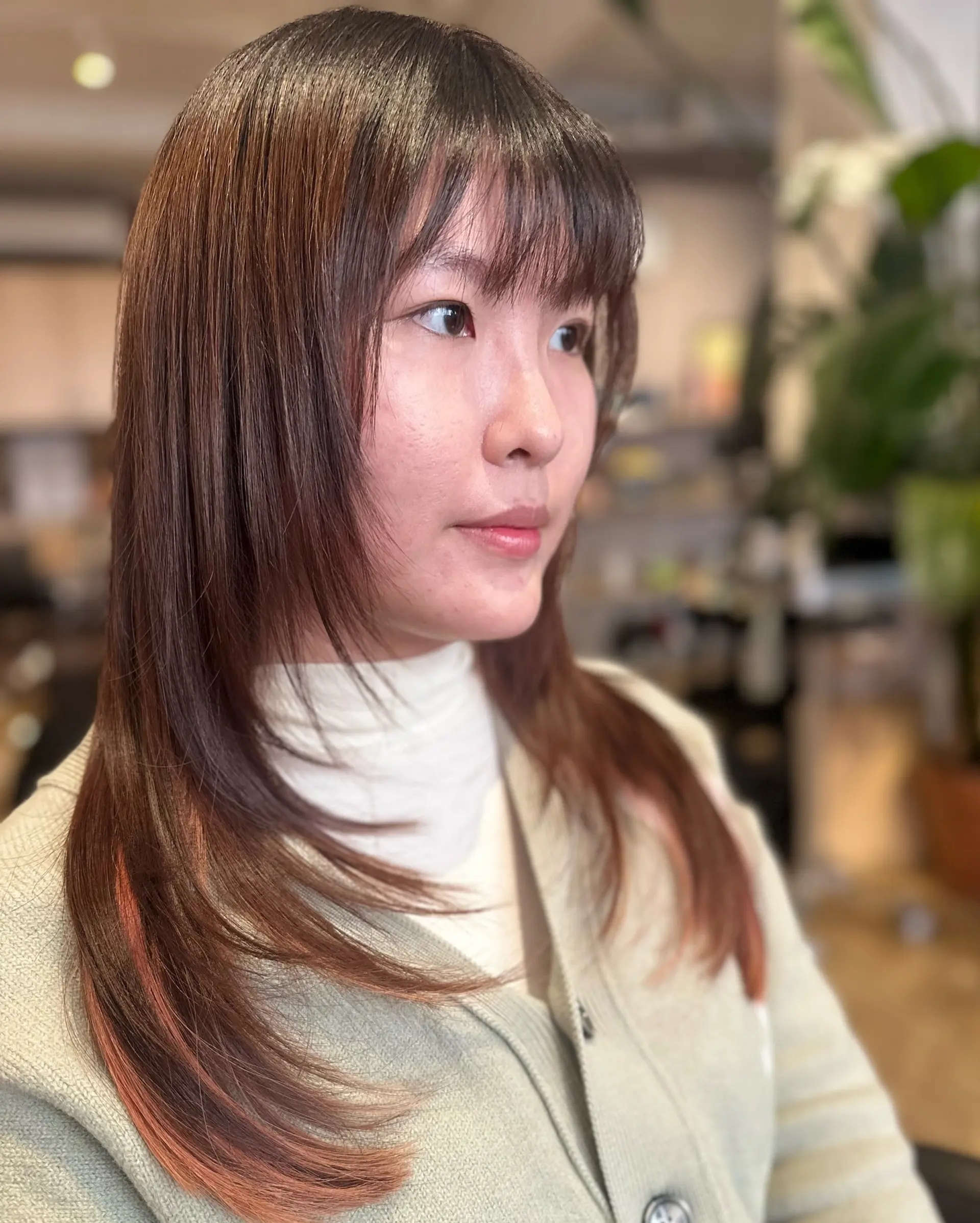 Long straight brunette haircut featuring wispy front bangs and tapered face-framing layers. 1