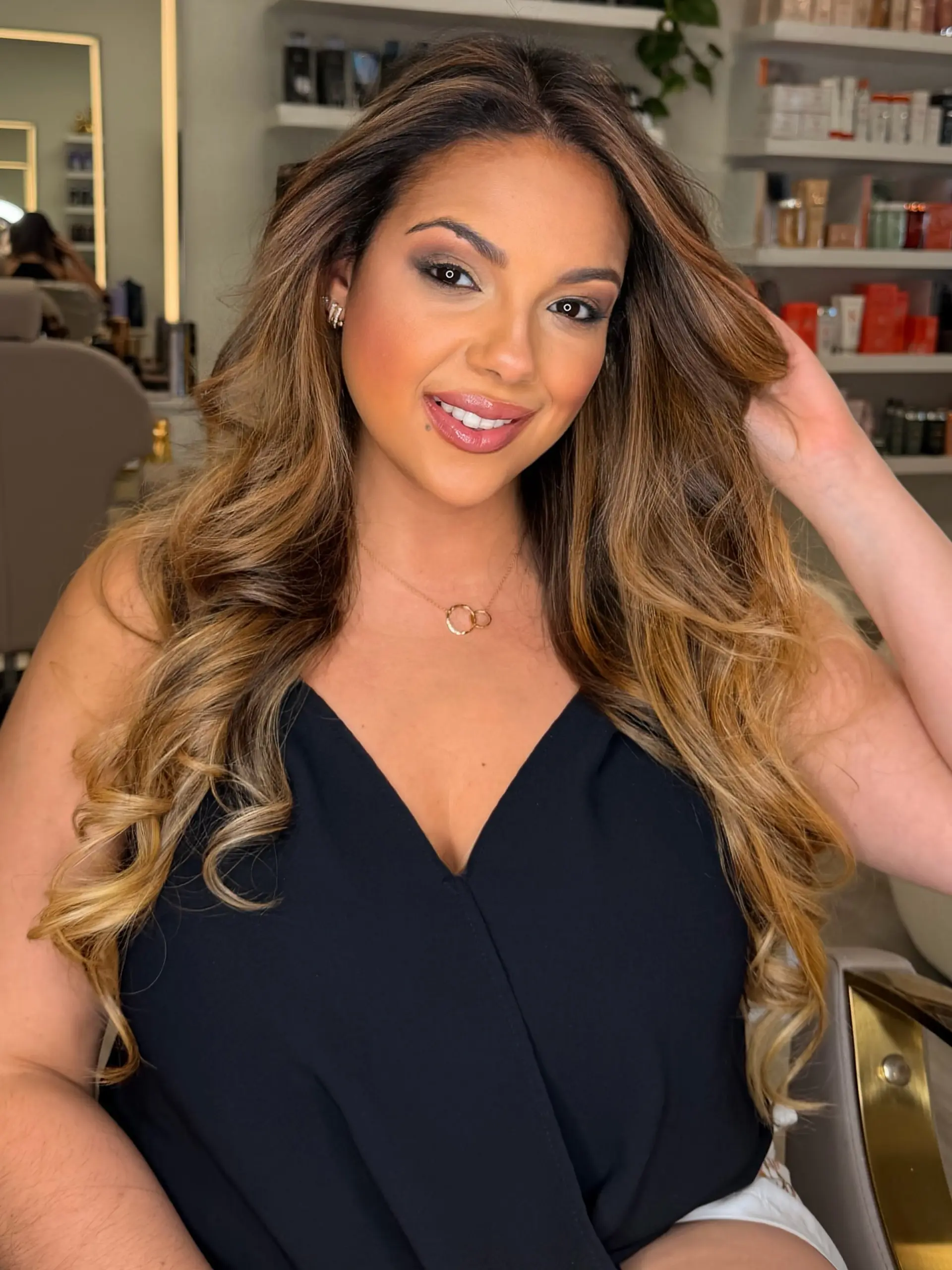 Long flowing hair featuring a seamless dimensional blonde balayage styled in voluminous, polished waves. 1
