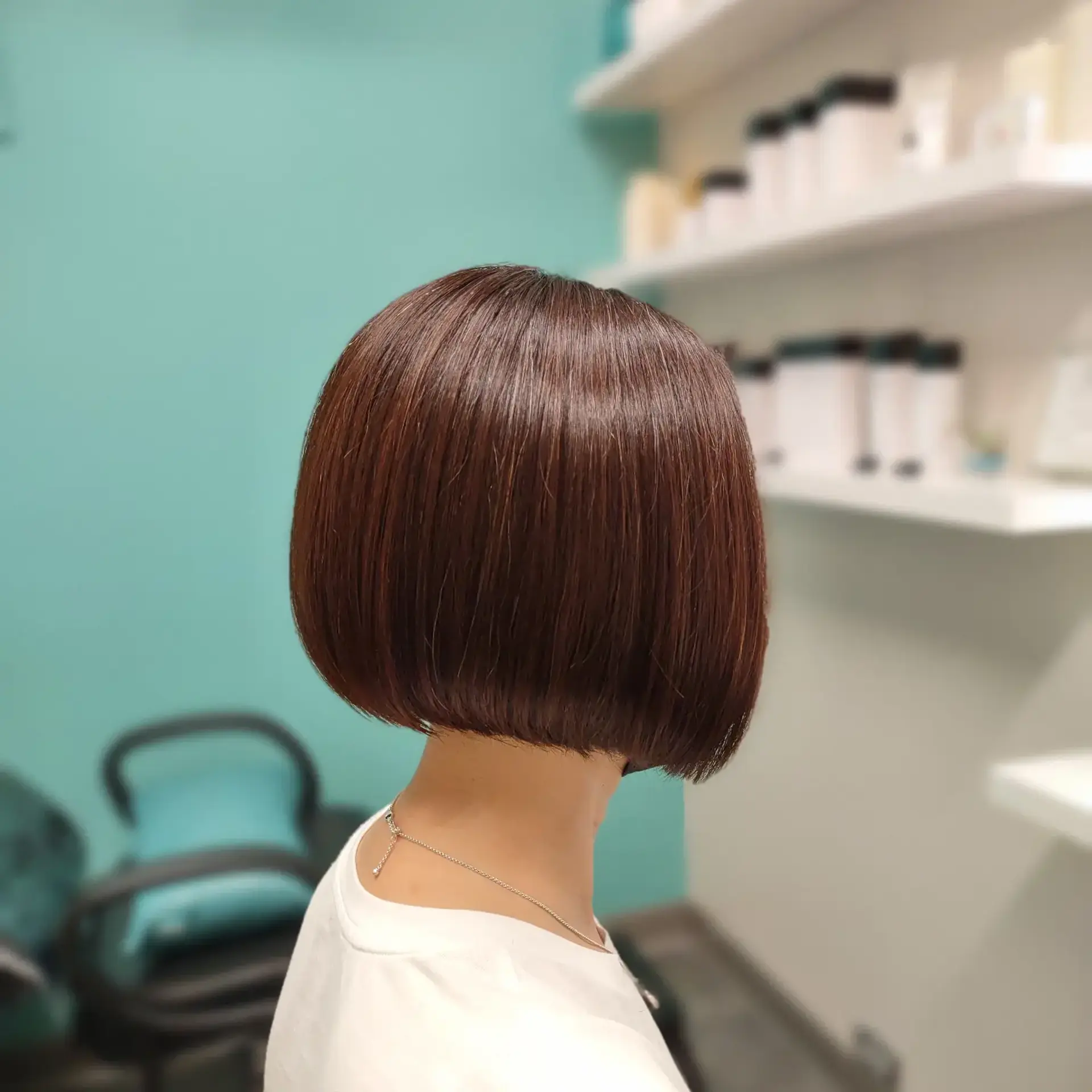 A sleek, chin-length rounded bob haircut styled pin-straight with a high-shine warm brown tone. 1