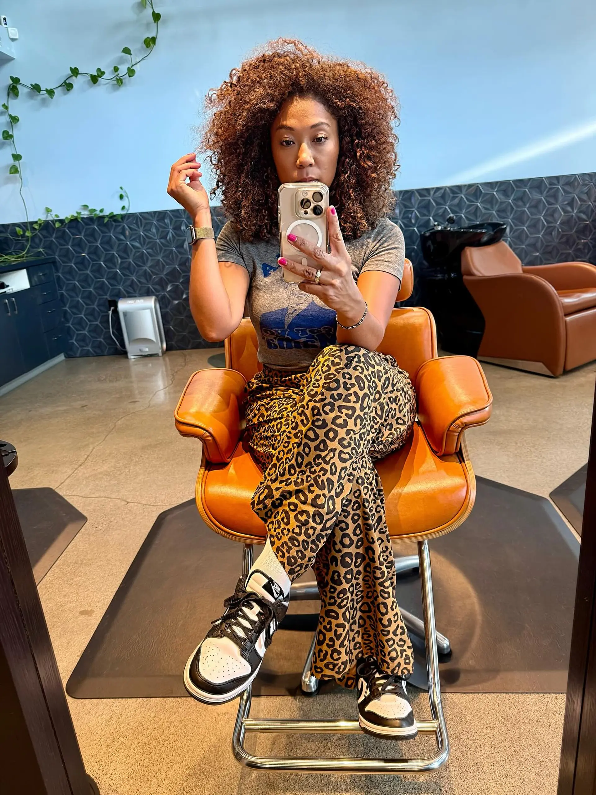 A voluminous, rounded shoulder-length curly haircut with defined ringlets and warm caramel highlights. 1