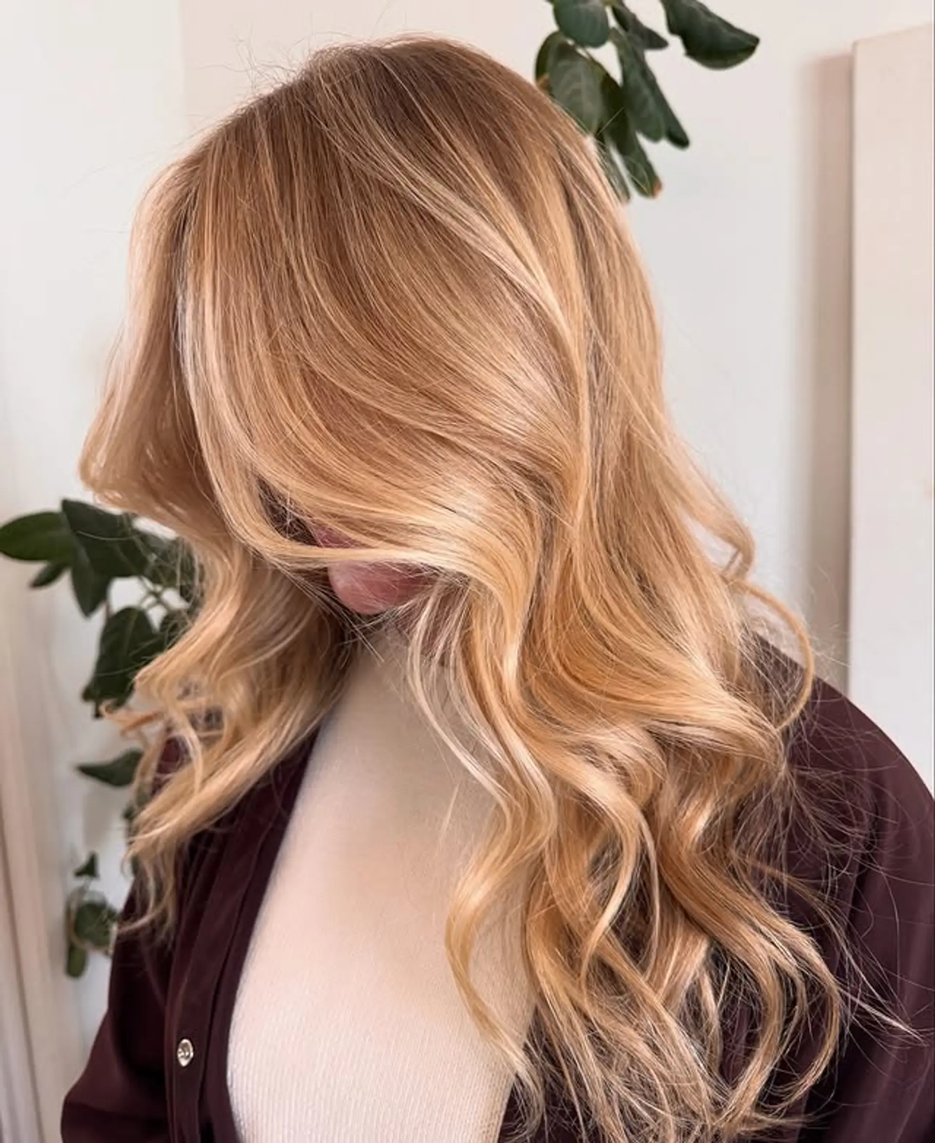 A long, wavy hairstyle with a golden blonde balayage and face-framing layers. 1