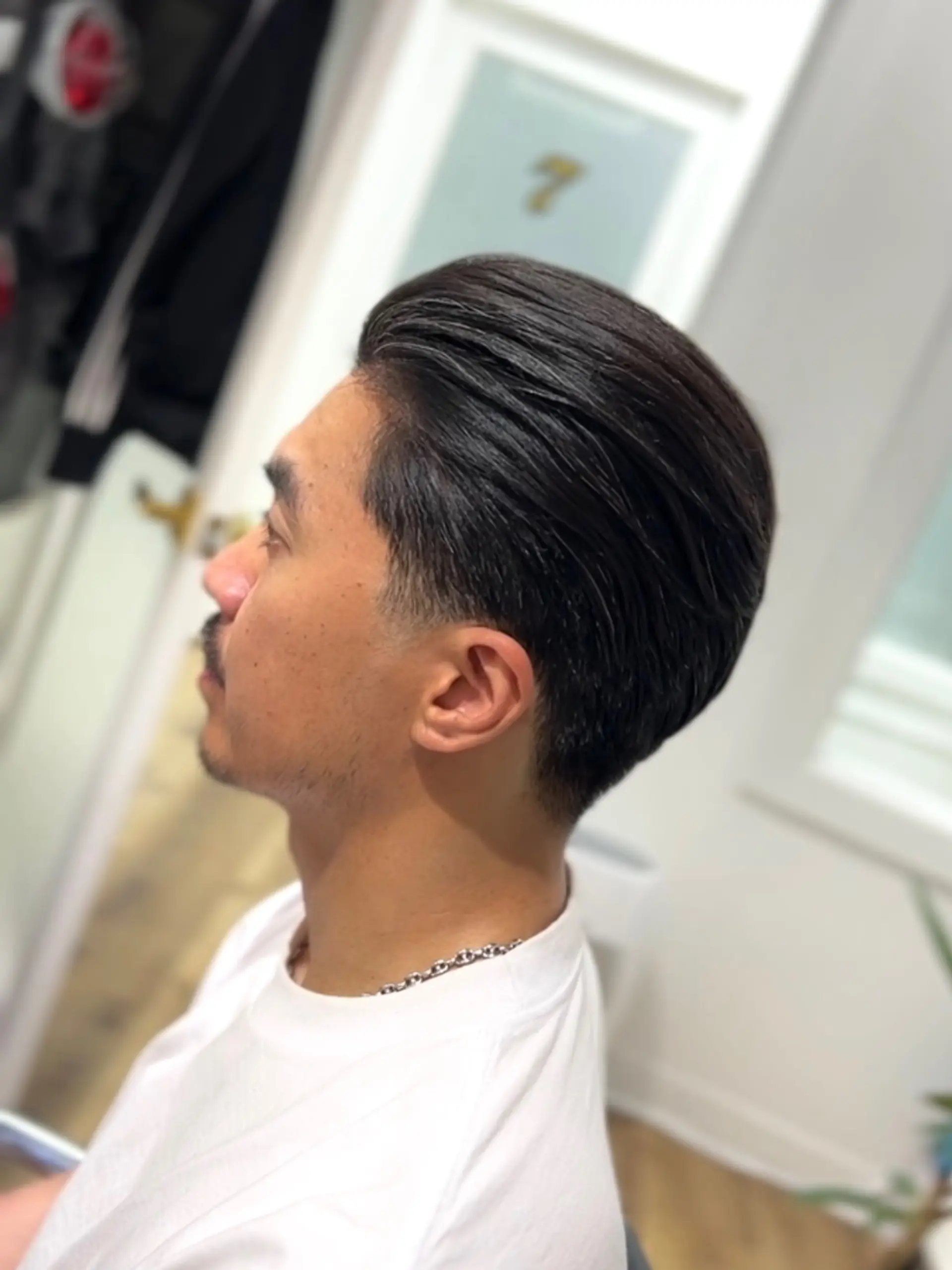 A sleek, slicked-back style featuring smoothly swept hair on top and neat, tapered sides. 1