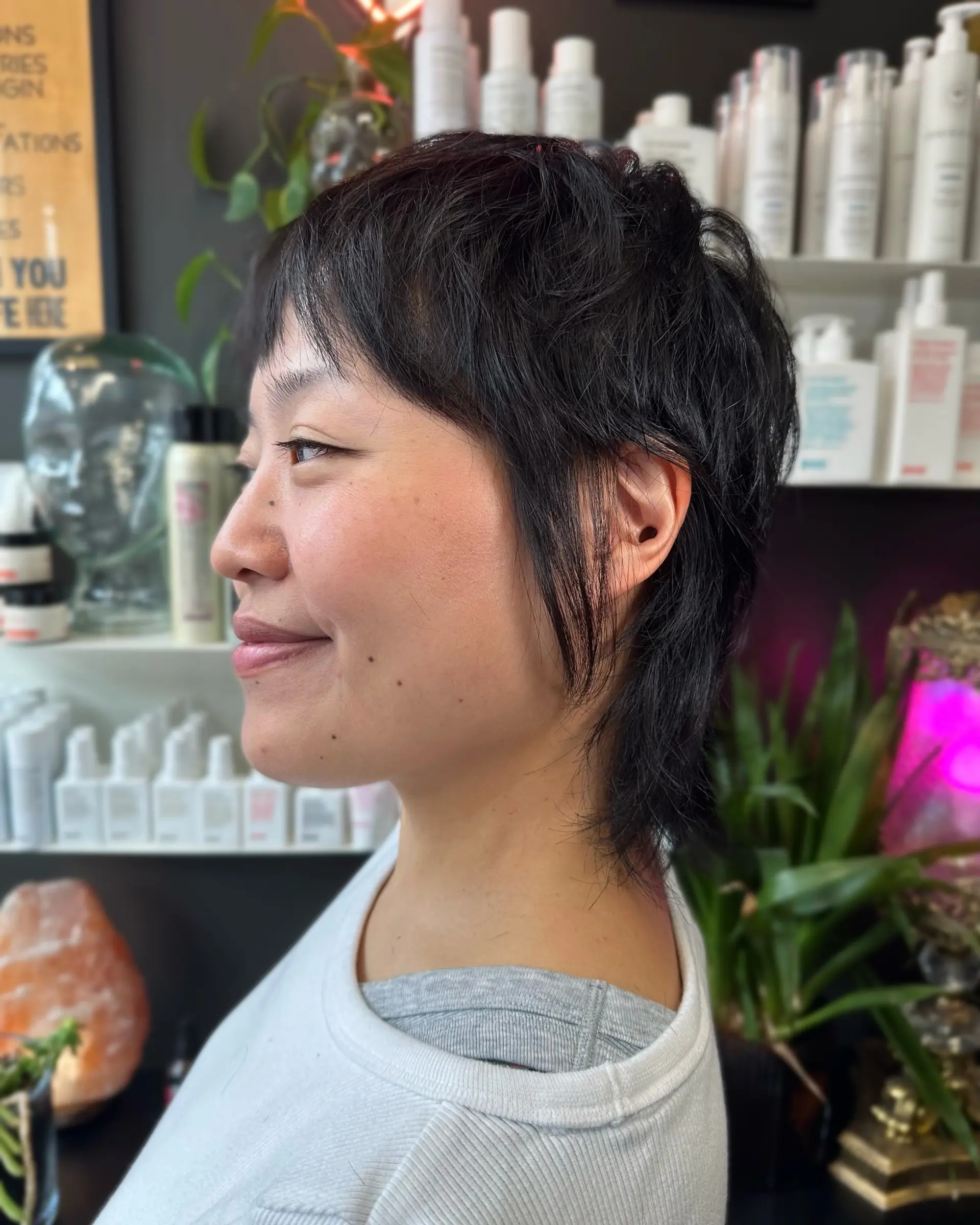 A textured black pixie shag haircut featuring wispy micro fringe, piecey sideburns, and a soft, elongated nape. 1
