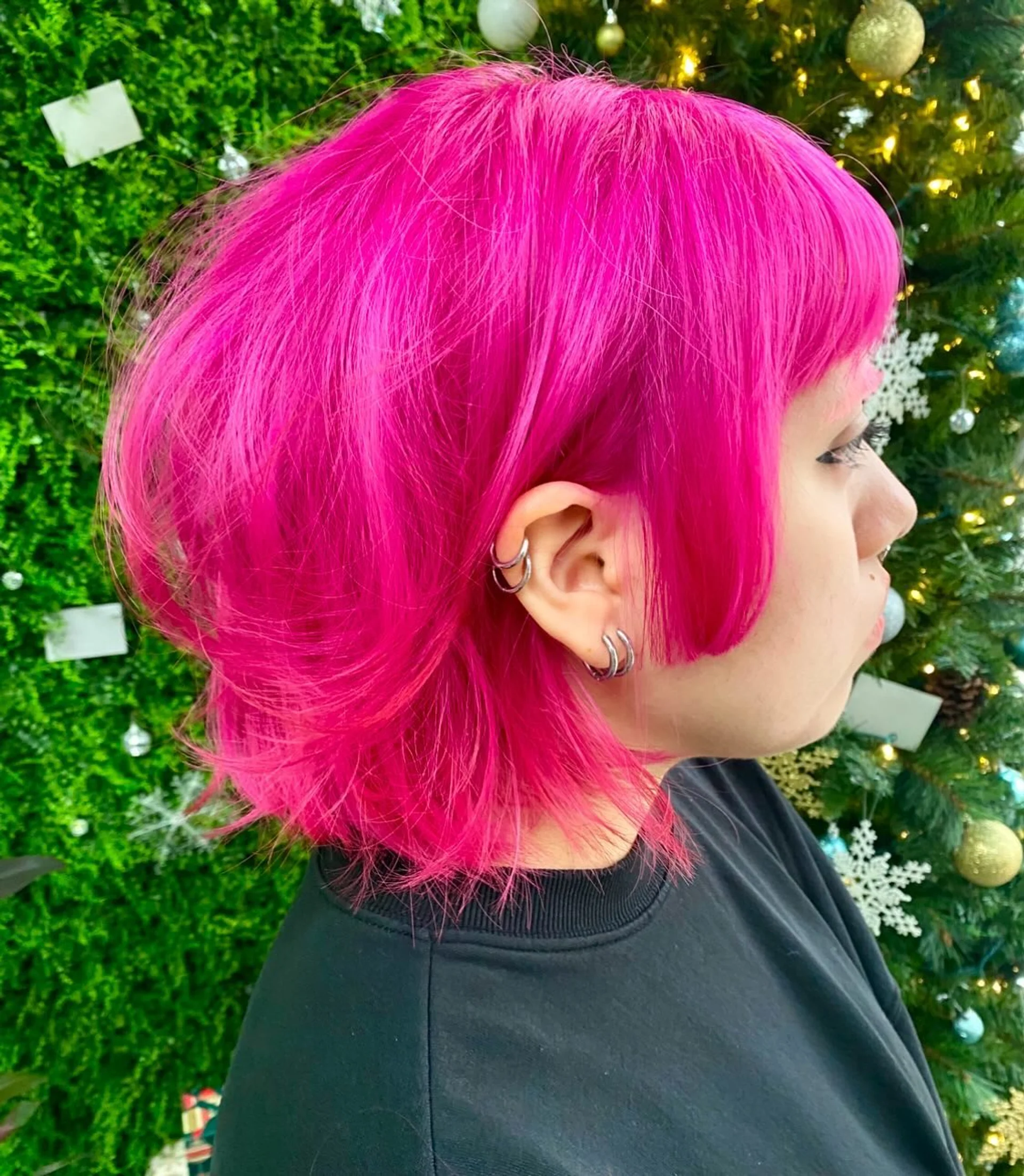 A woman with medium-length wavy hair featuring a vibrant ombre color melt from dark roots to red, pink, and purple, showcasing the Electric Fuchsia trend for 2026. - Preview 1