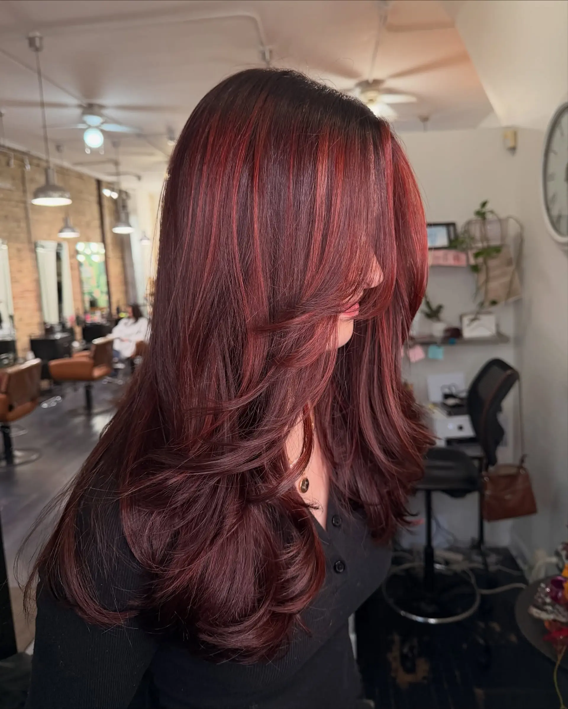 Long deep mahogany and vibrant red layered haircut styled with a voluminous, smooth blowout. 1