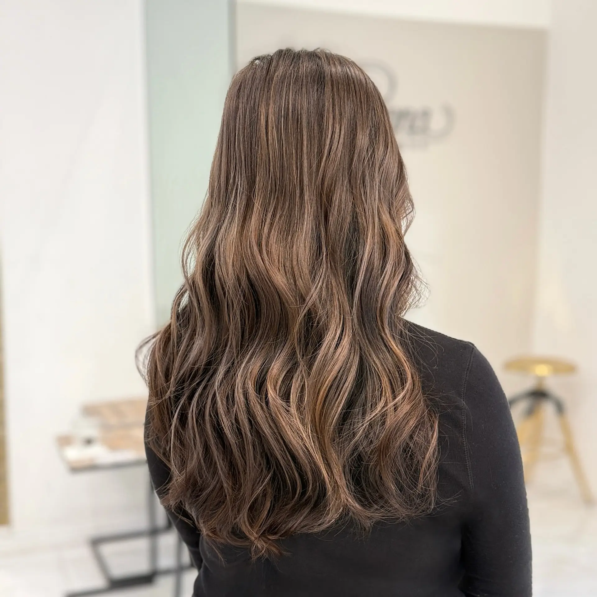 Long ash brown hair featuring a soft balayage blend styled in voluminous, polished waves. 1