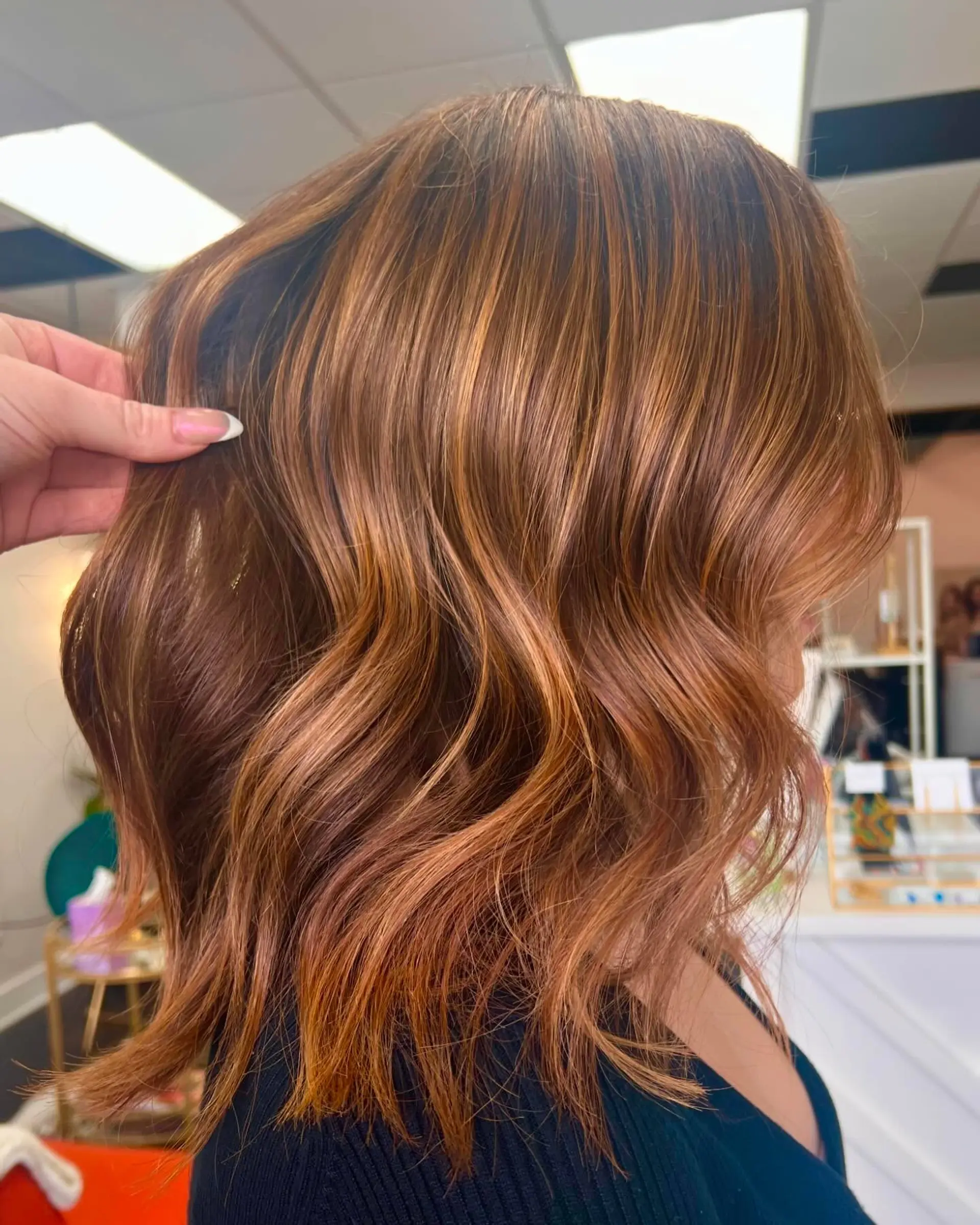 Shoulder-length textured lob styled with loose waves and dimensional copper highlights. 1