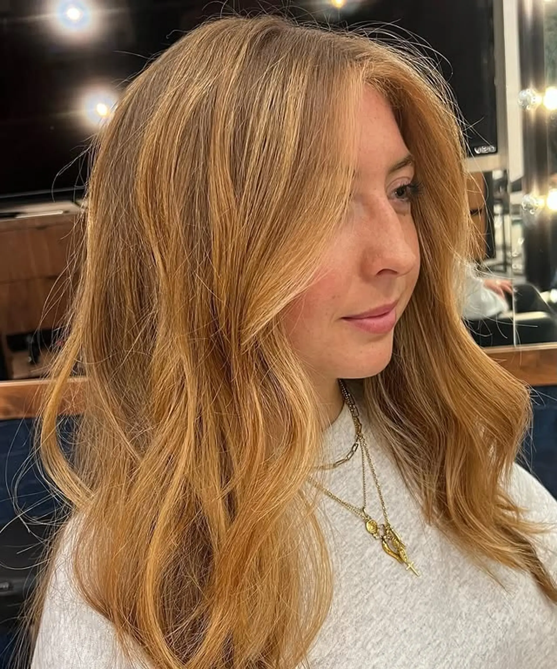 A layered medium hairstyle with face-framing layers and soft waves. 1