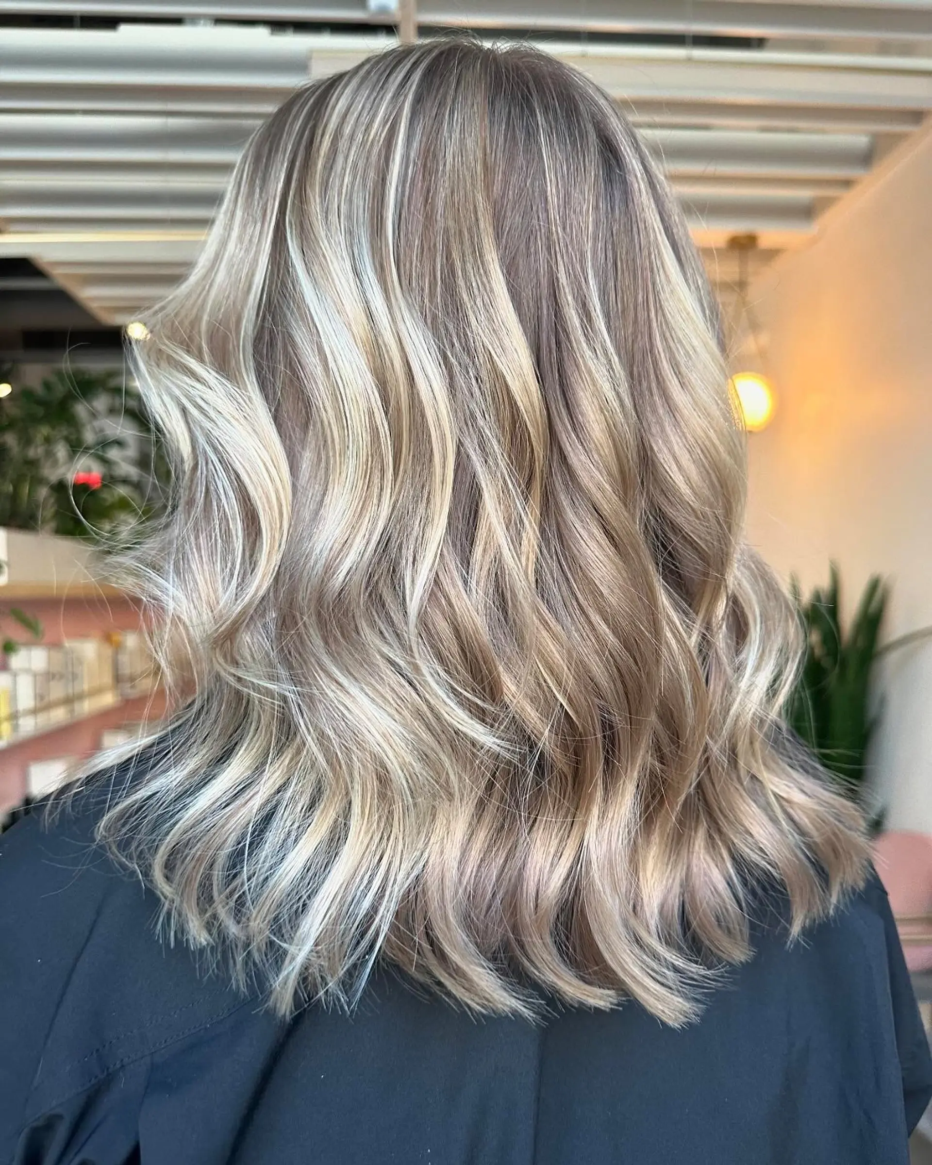Shoulder-length textured lob styled in soft, loose waves with dimensional cool-toned blonde highlights. 1