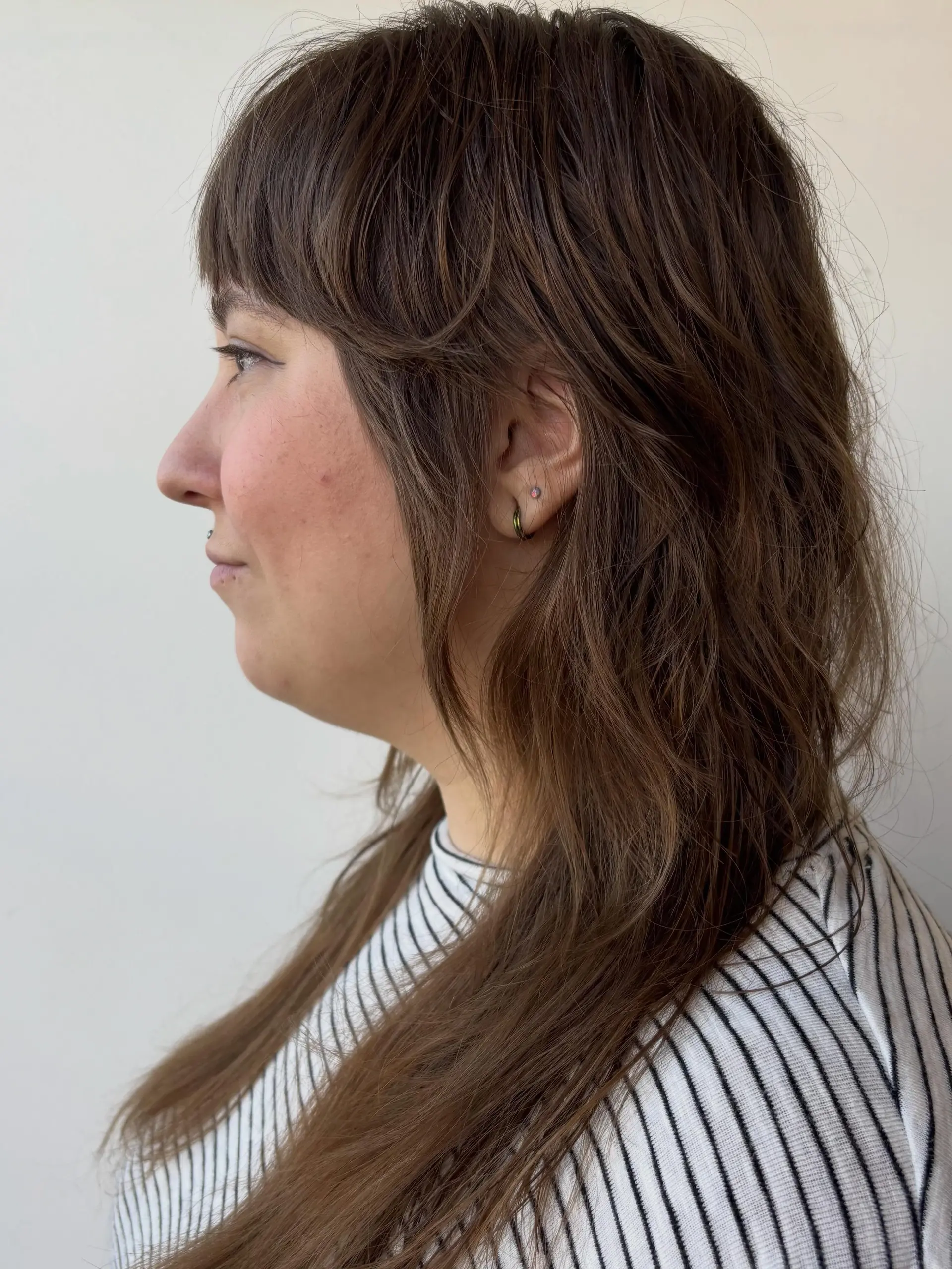 A textured brunette shag haircut with full fringe bangs and heavily layered, face-framing lengths. 1
