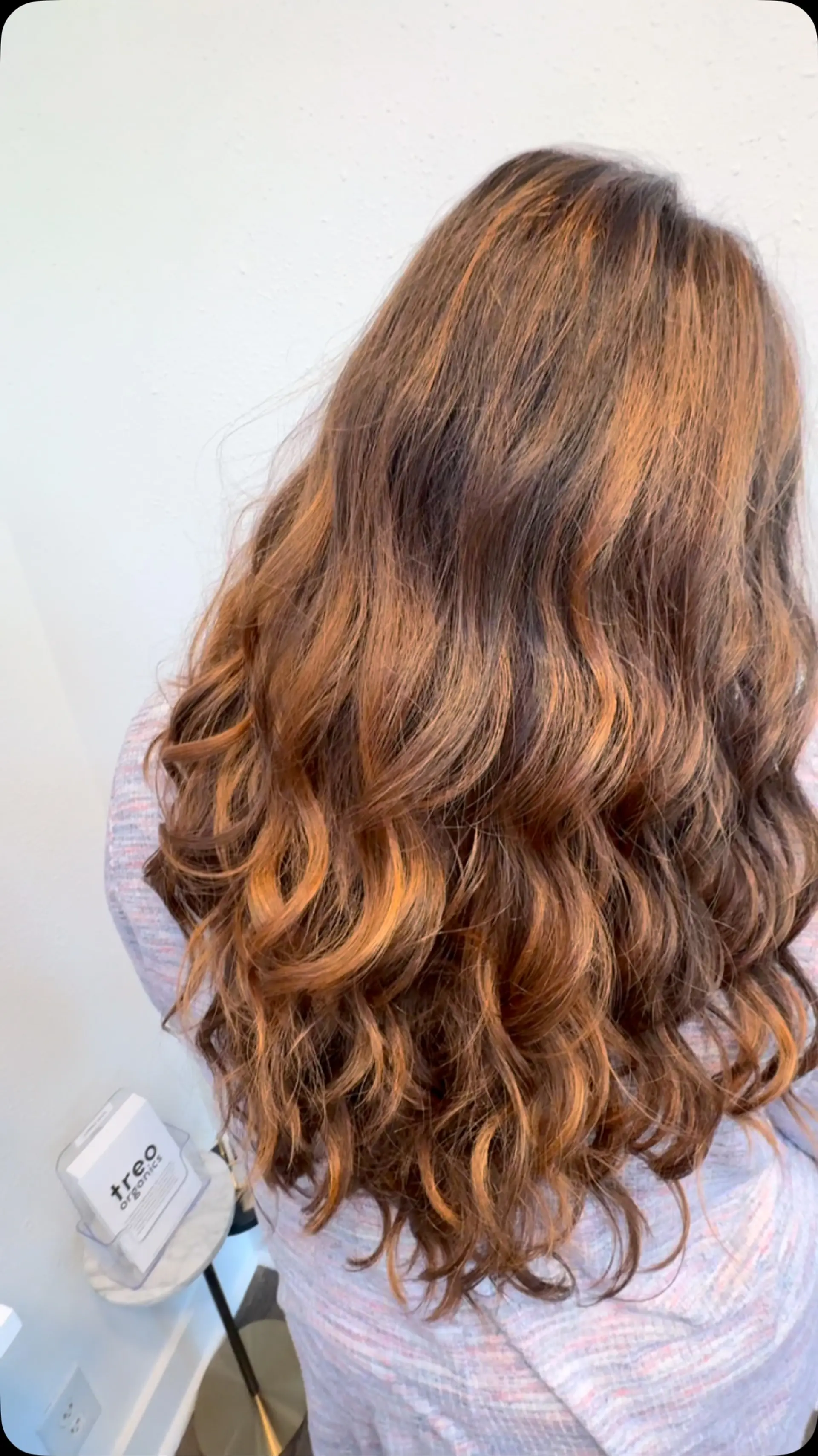Long brunette hair enhanced with dimensional warm copper and caramel balayage highlights, styled in loose, textured waves. 1