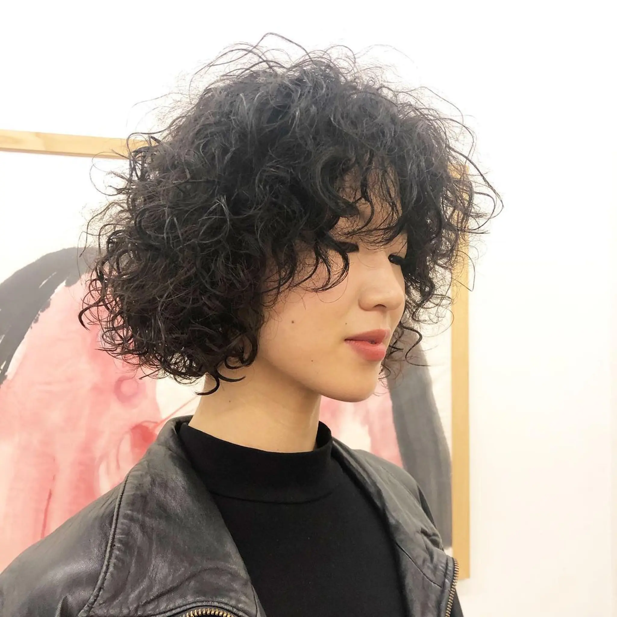 A short, black, curly bob cut characterized by voluminous curls and rich texture. Spiral Perm by @takeohair