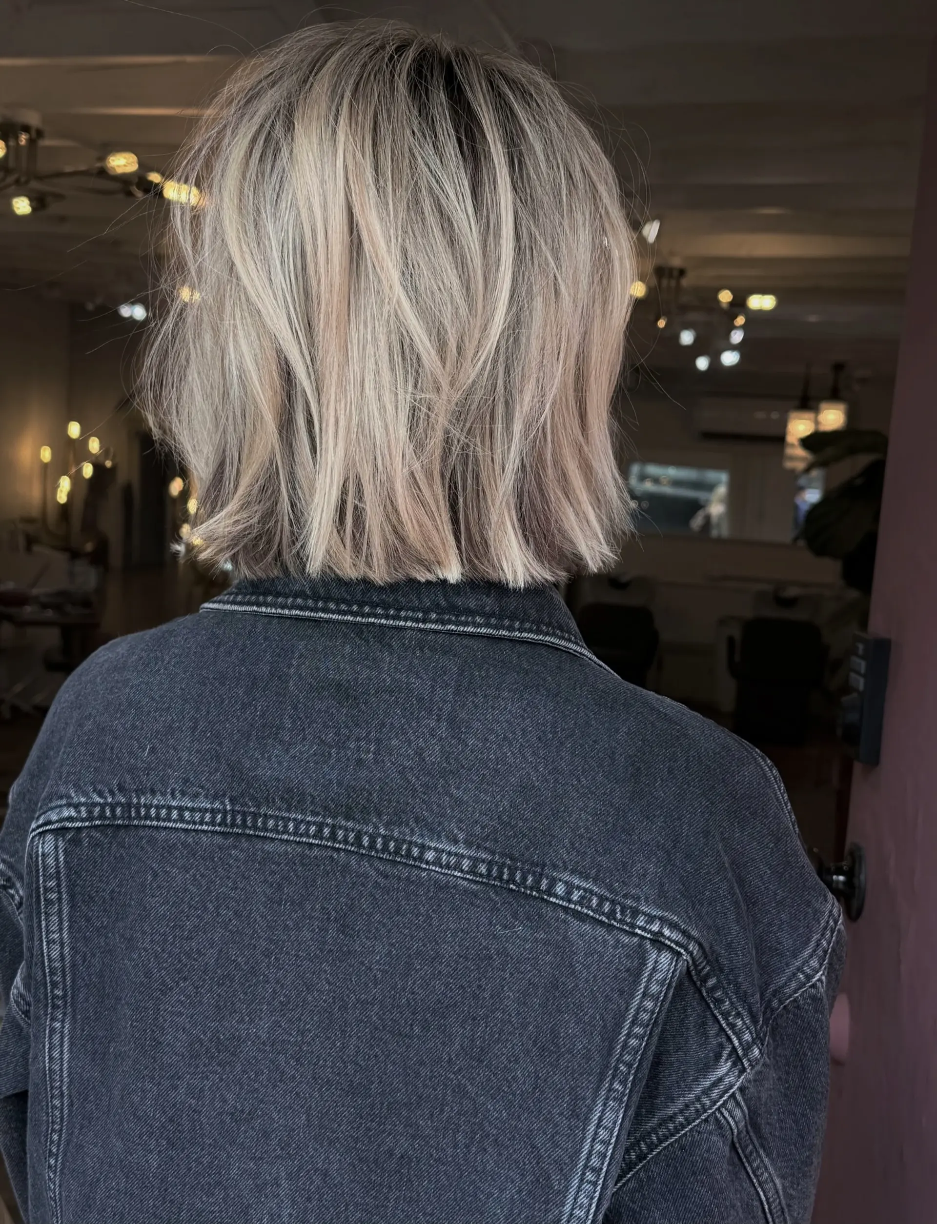 A blunt-cut, textured box bob featuring dimensional cool blonde highlights and a soft natural root. 1
