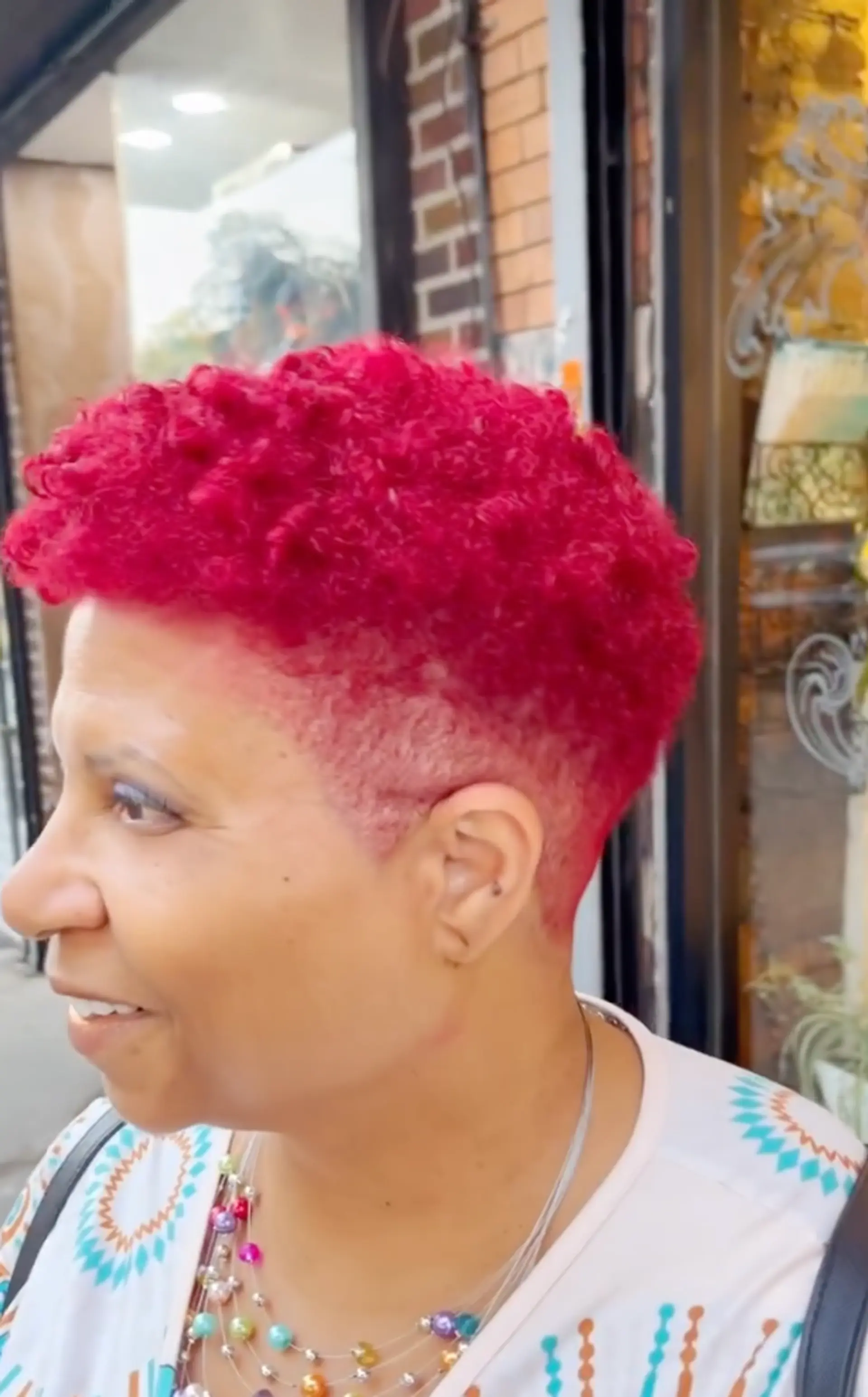 Short curly pixie cut with tapered sides and bold color. 1