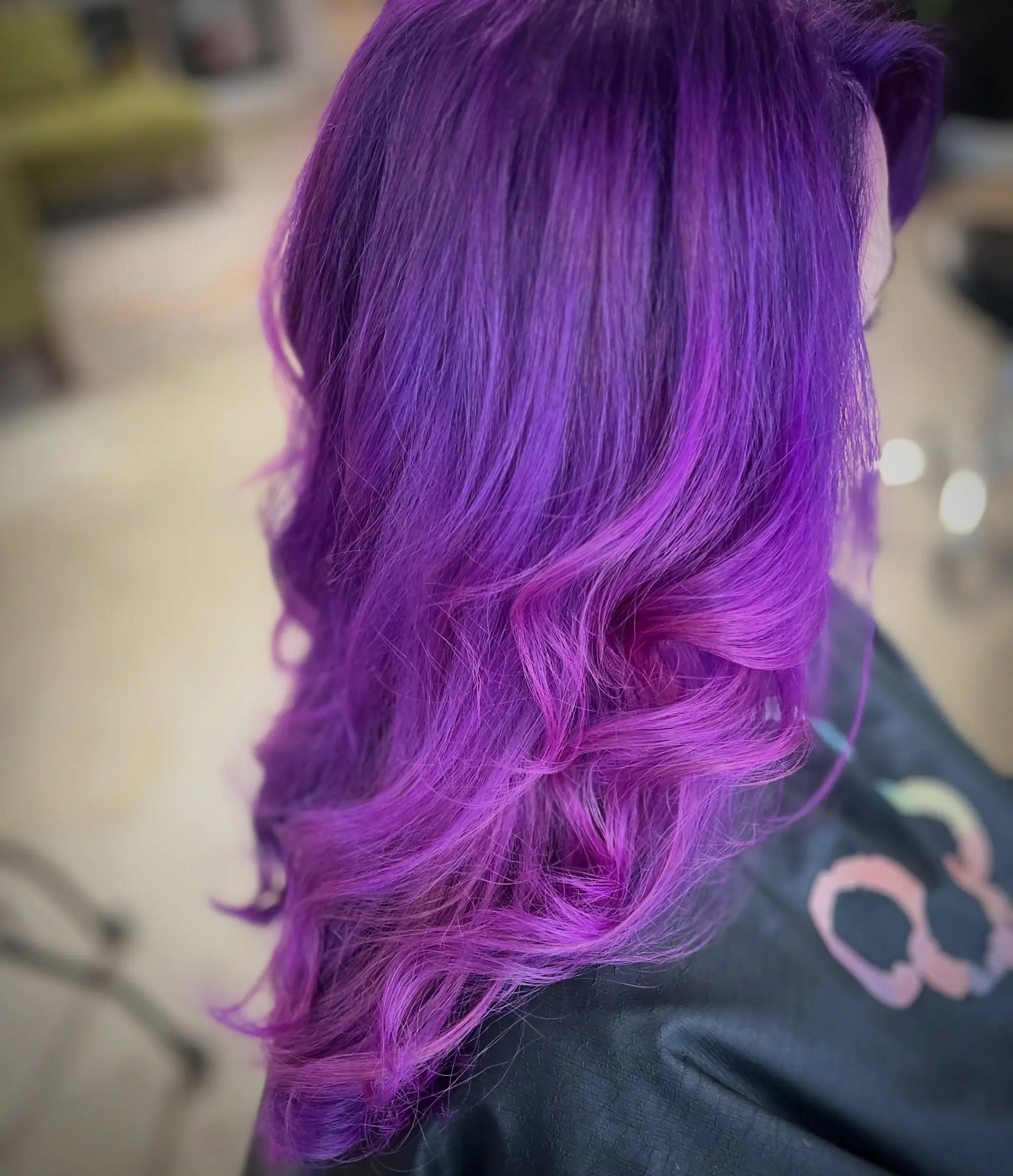 A vivid color melt transitioning from deep purple roots to bright magenta-violet ends, styled with loose cascading curls. 1