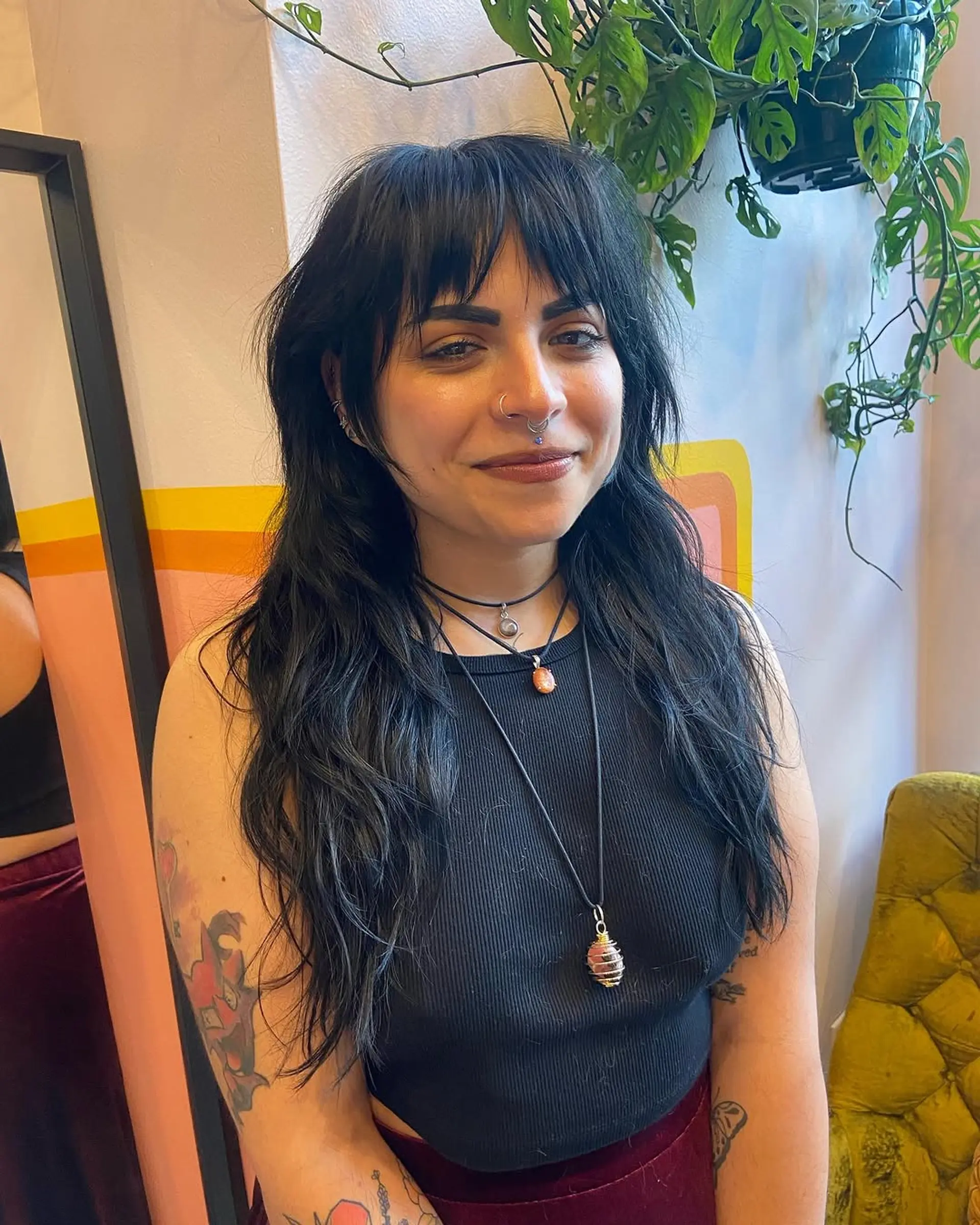 Long, black wavy hair with textured layers and choppy bangs, offering a bohemian, natural vibe. 2