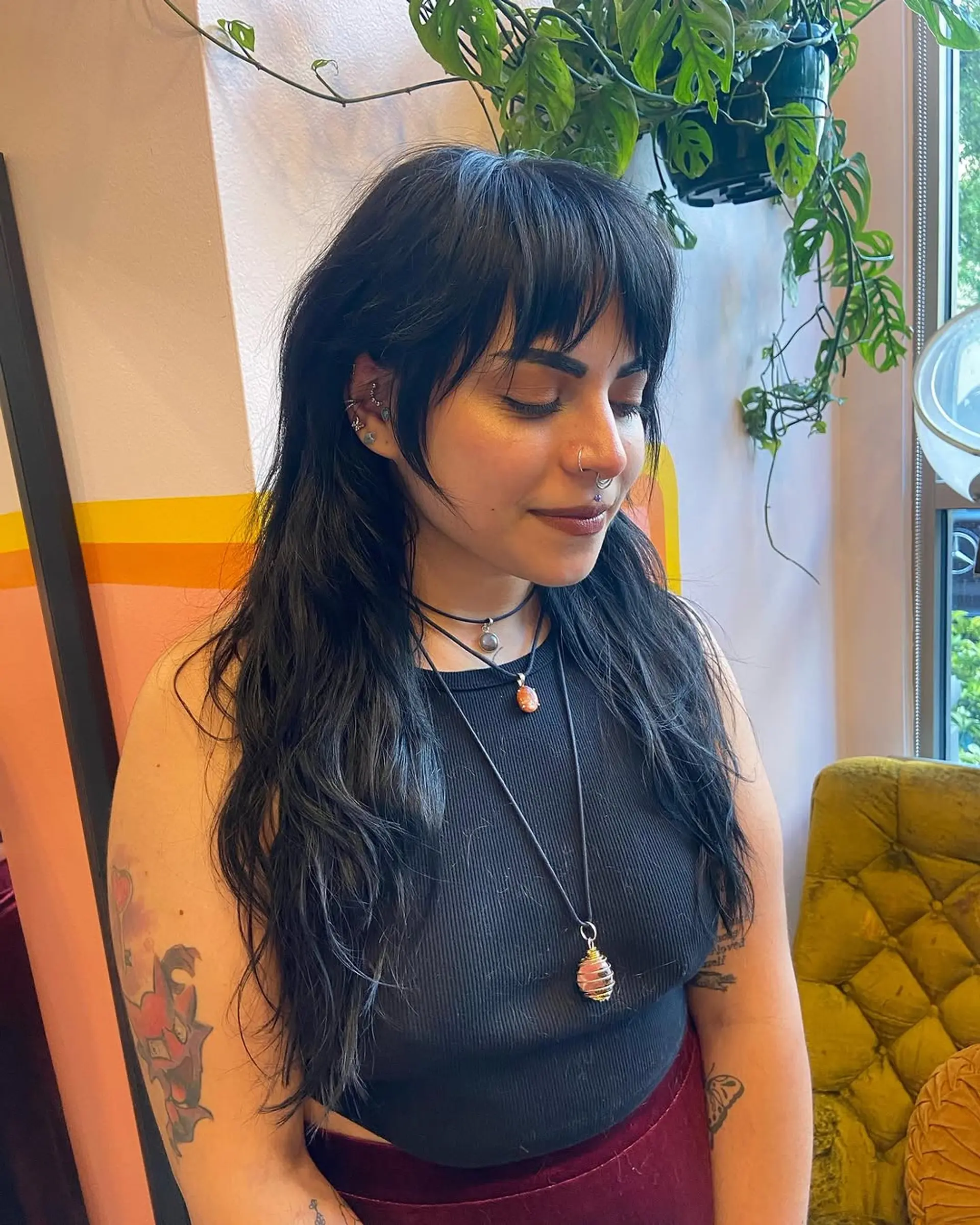 Long, black wavy hair with textured layers and choppy bangs, offering a bohemian, natural vibe. 1