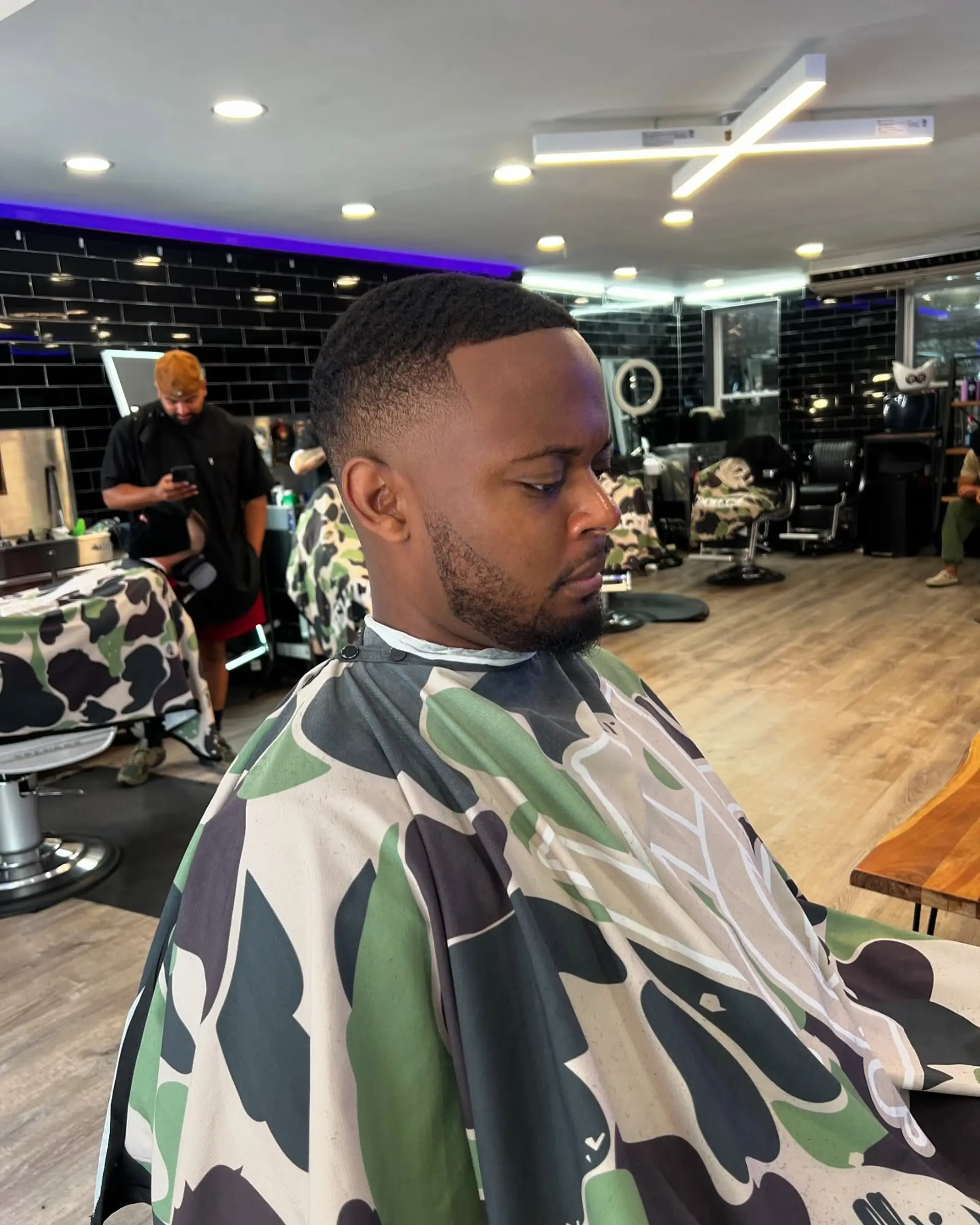 A clean short buzz cut featuring a smooth fade on the sides and back with a crisp line-up along the hairline. 1