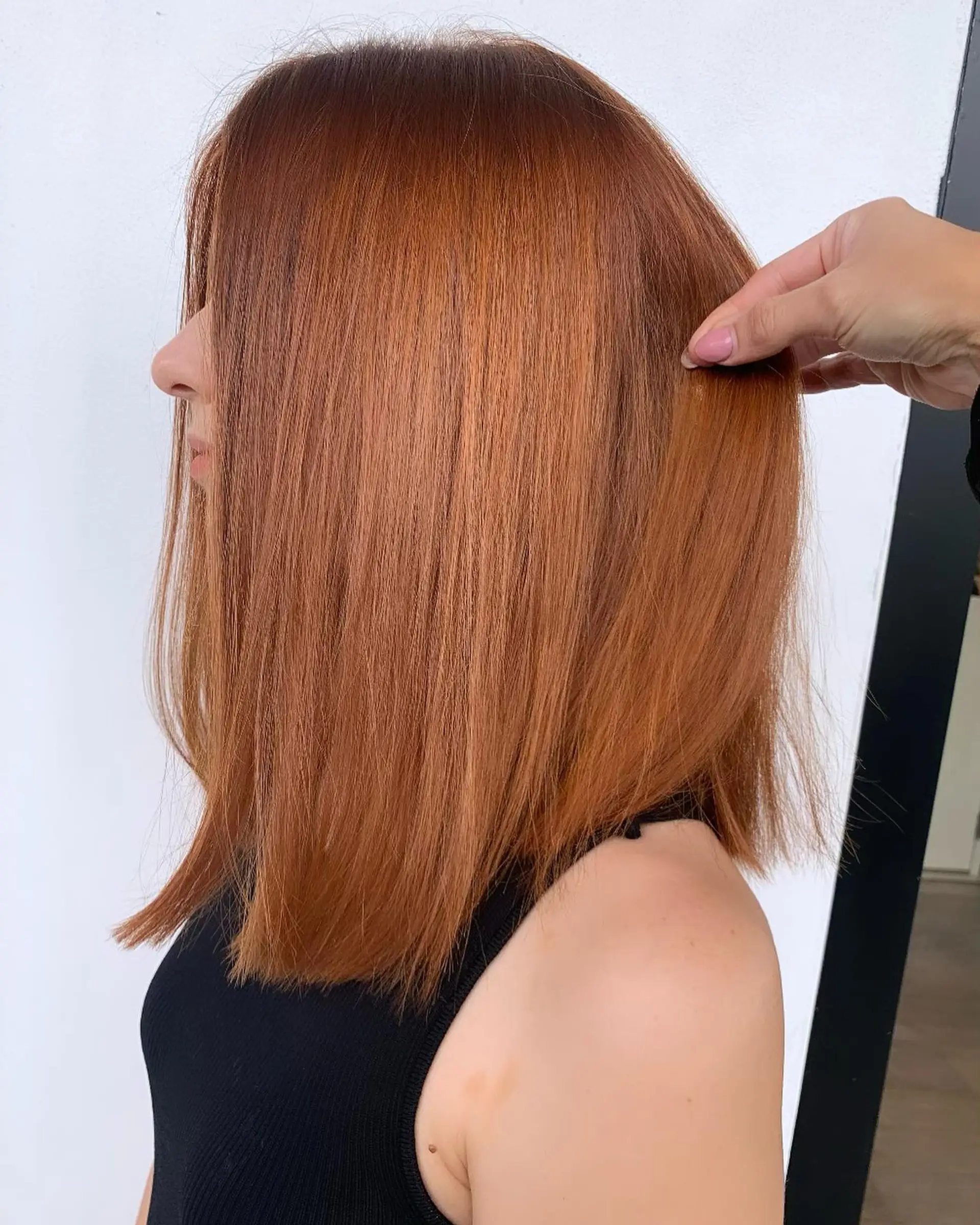 A sleek, shoulder-length blunt lob cut styled straight in a vibrant copper tone. 1